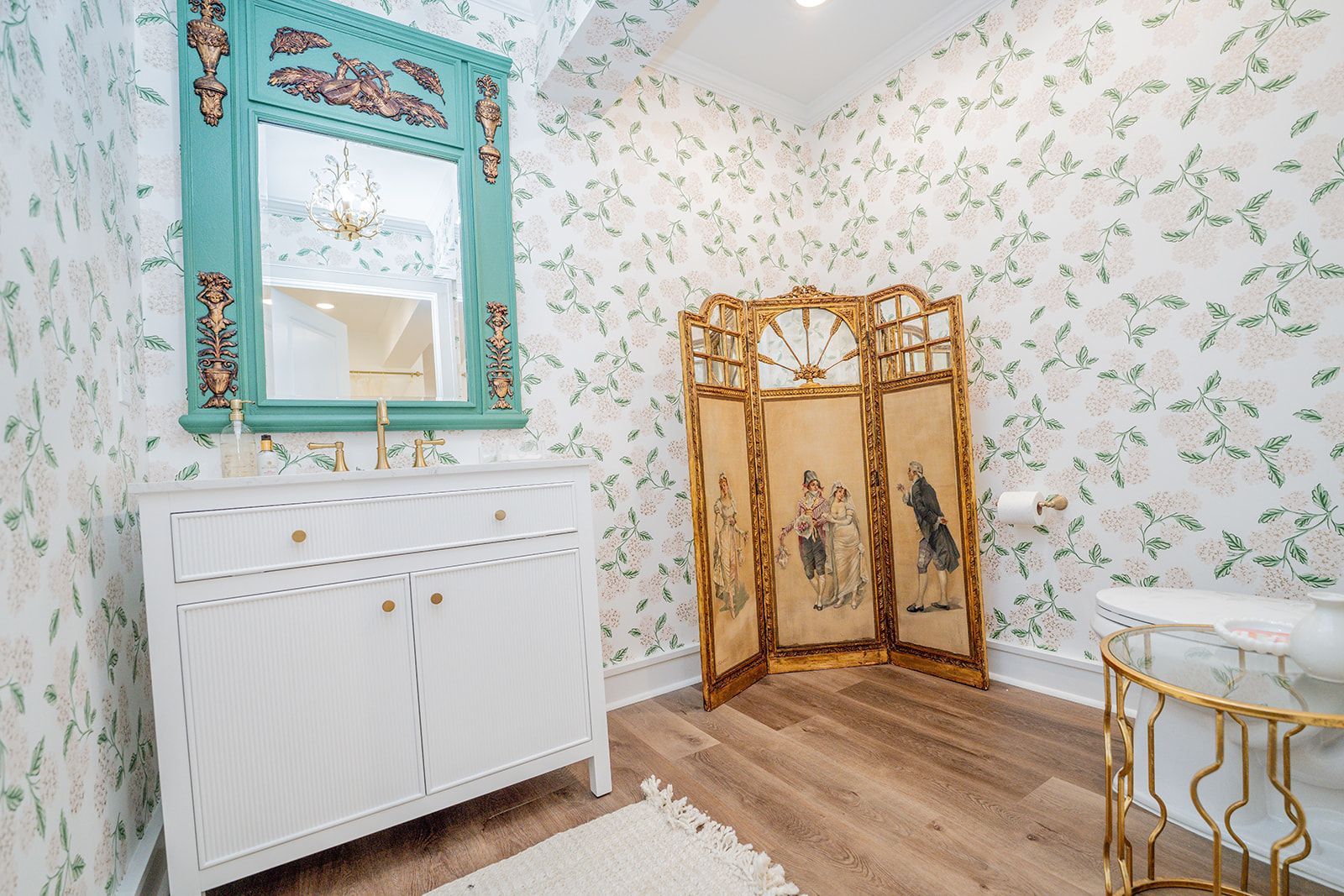 A room with a mirror , dresser , table and screen.