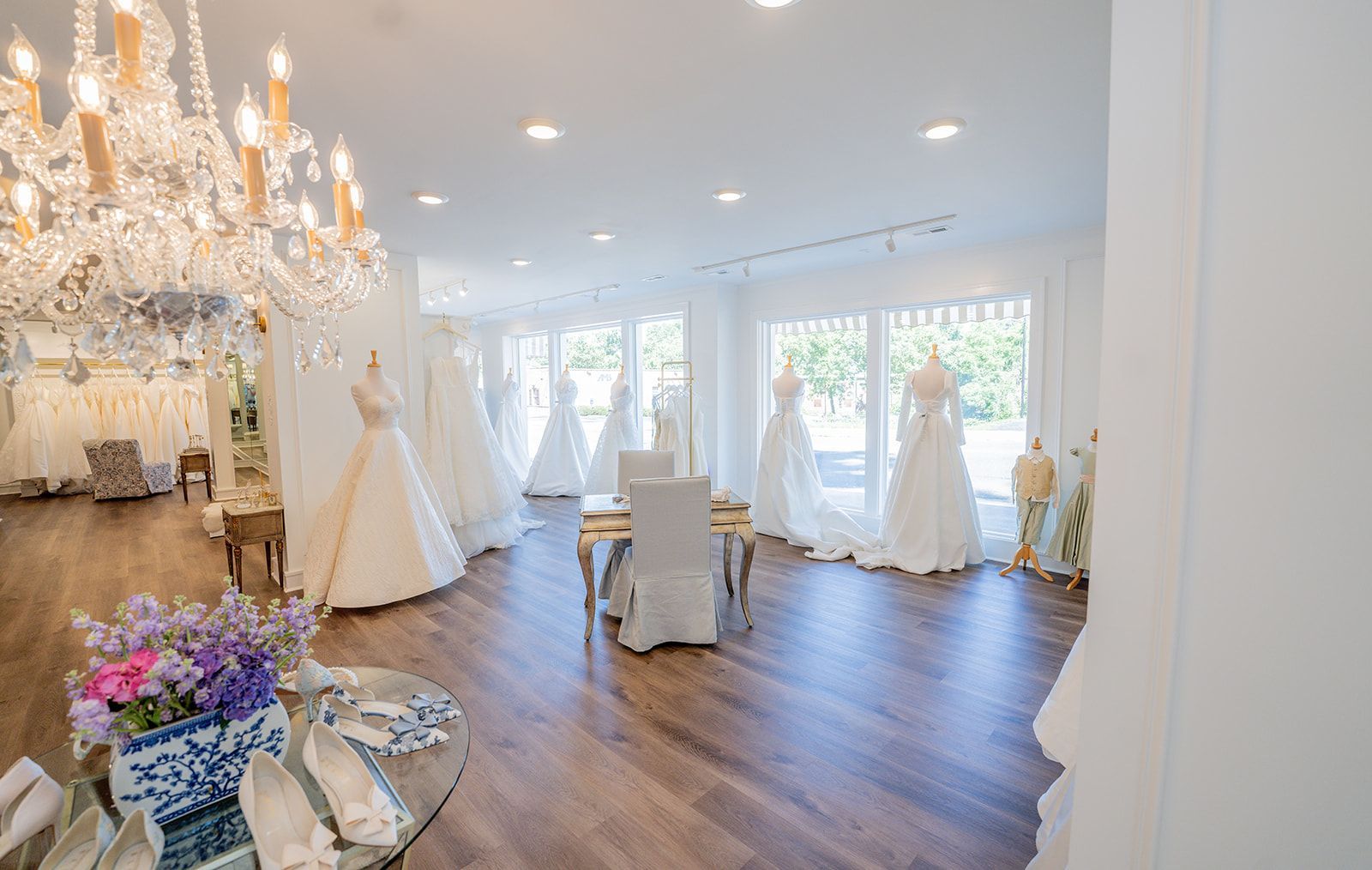 A large room filled with lots of wedding dresses and a chandelier.