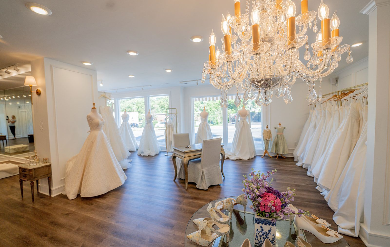 A large room filled with lots of wedding dresses and a chandelier.