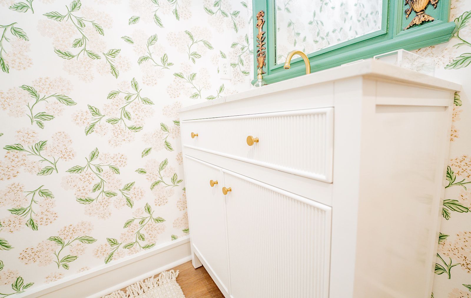 A bathroom with a sink , mirror and floral wallpaper.