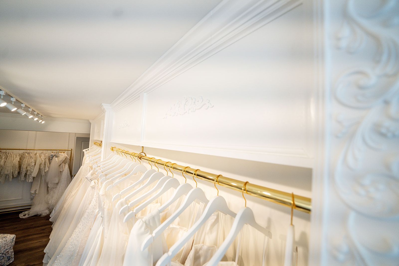 A row of white dresses hanging on a rack in a bridal shop.