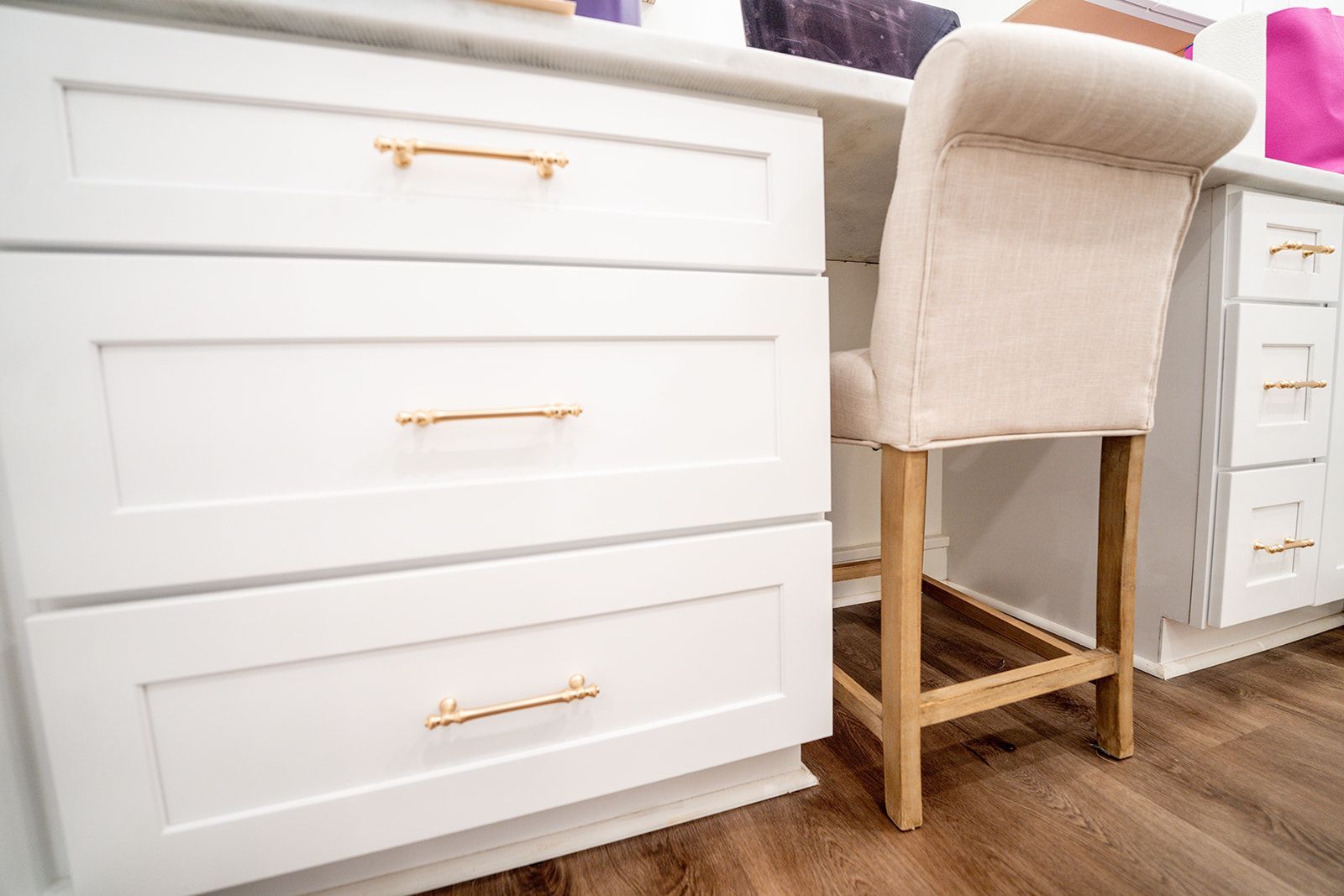 A chair is sitting next to a desk with drawers in a room.