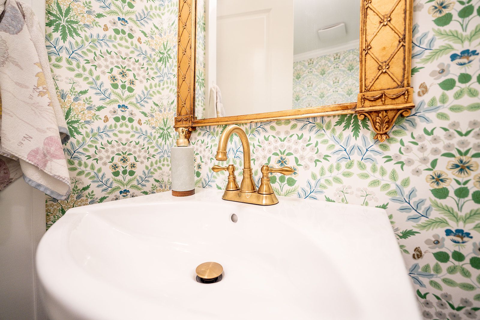 A bathroom sink with a gold faucet and a mirror.