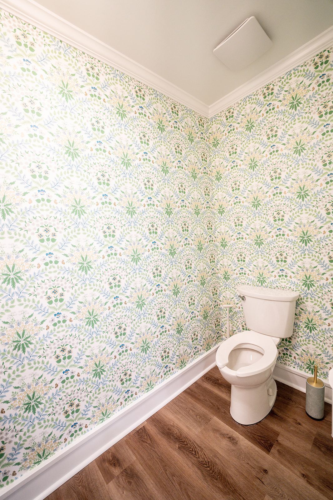 A bathroom with a toilet and floral wallpaper on the walls.