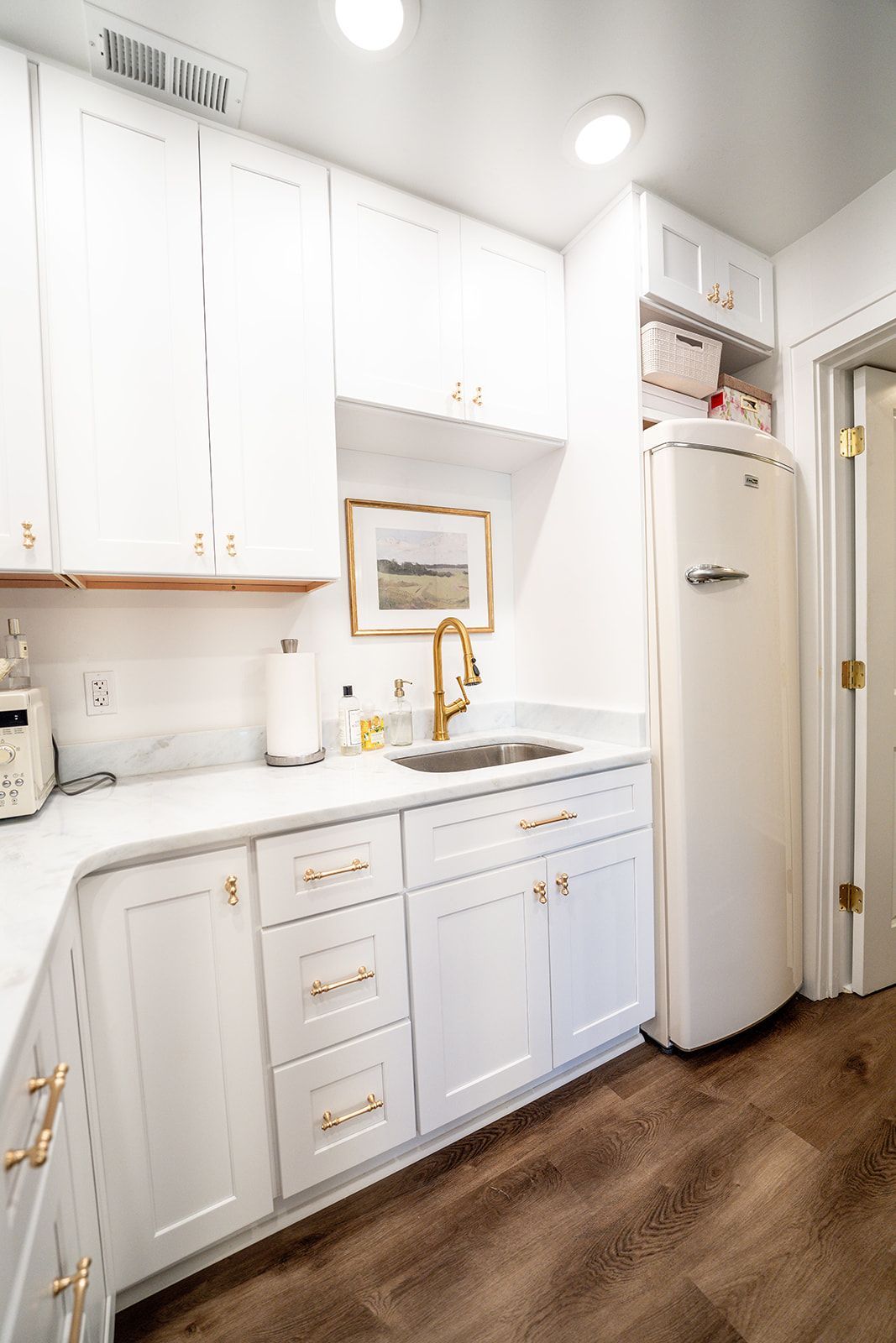A kitchen with white cabinets , a sink , and a refrigerator.