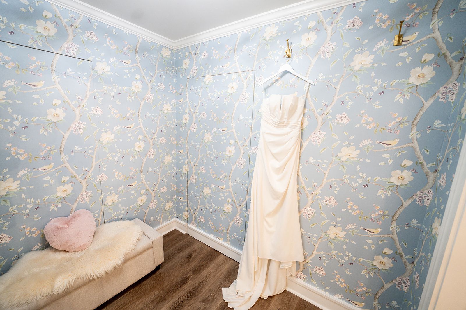 A wedding dress is hanging on a hanger in a dressing room.