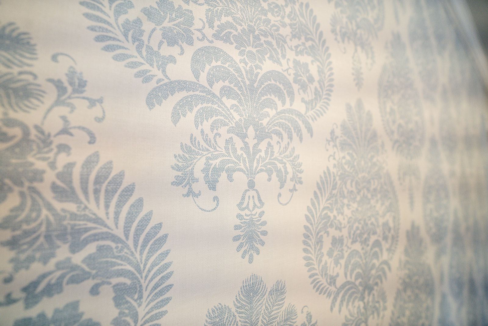 A close up of a blue and white damask wallpaper on a wall.