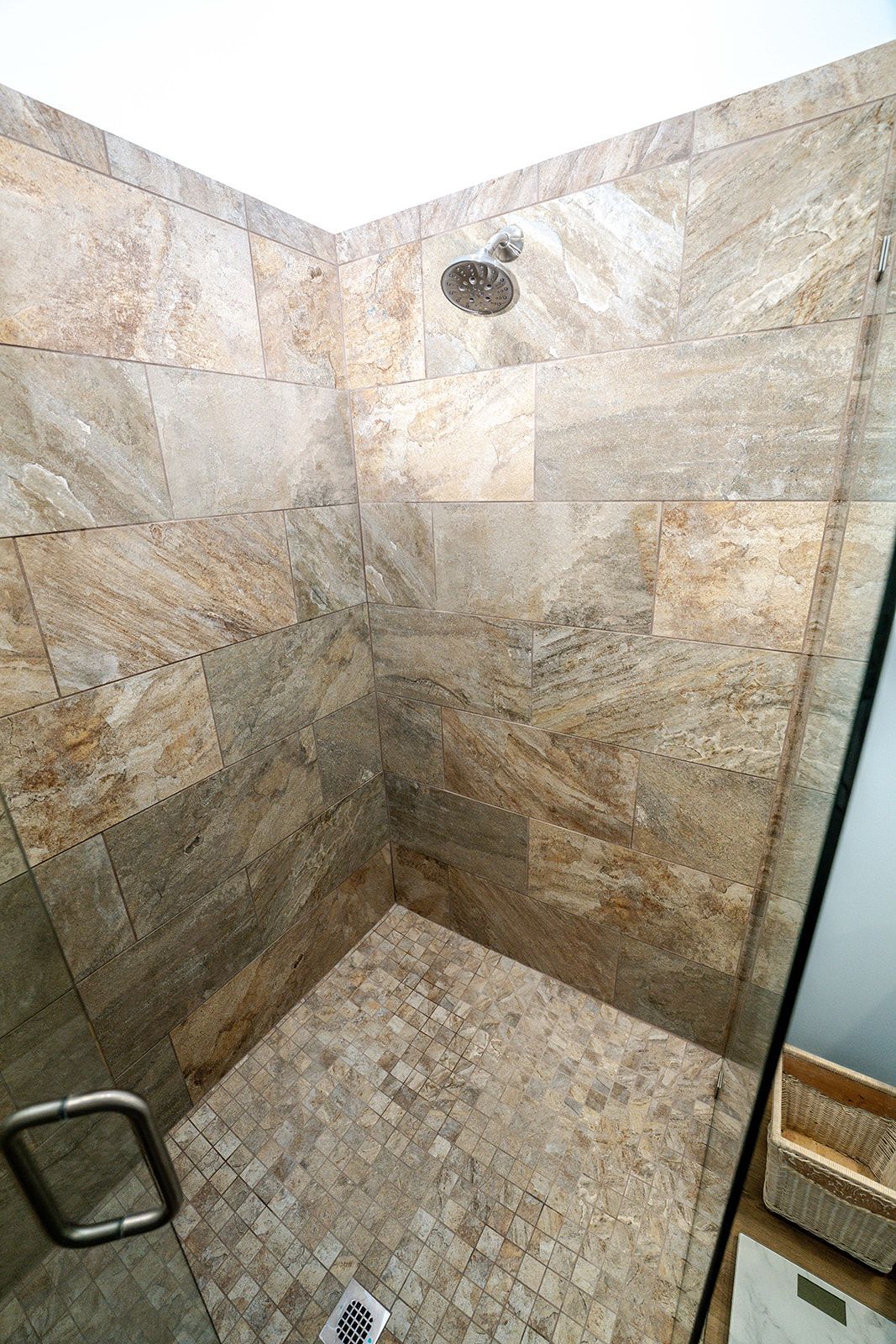 A walk in shower with tiled walls and a glass door.