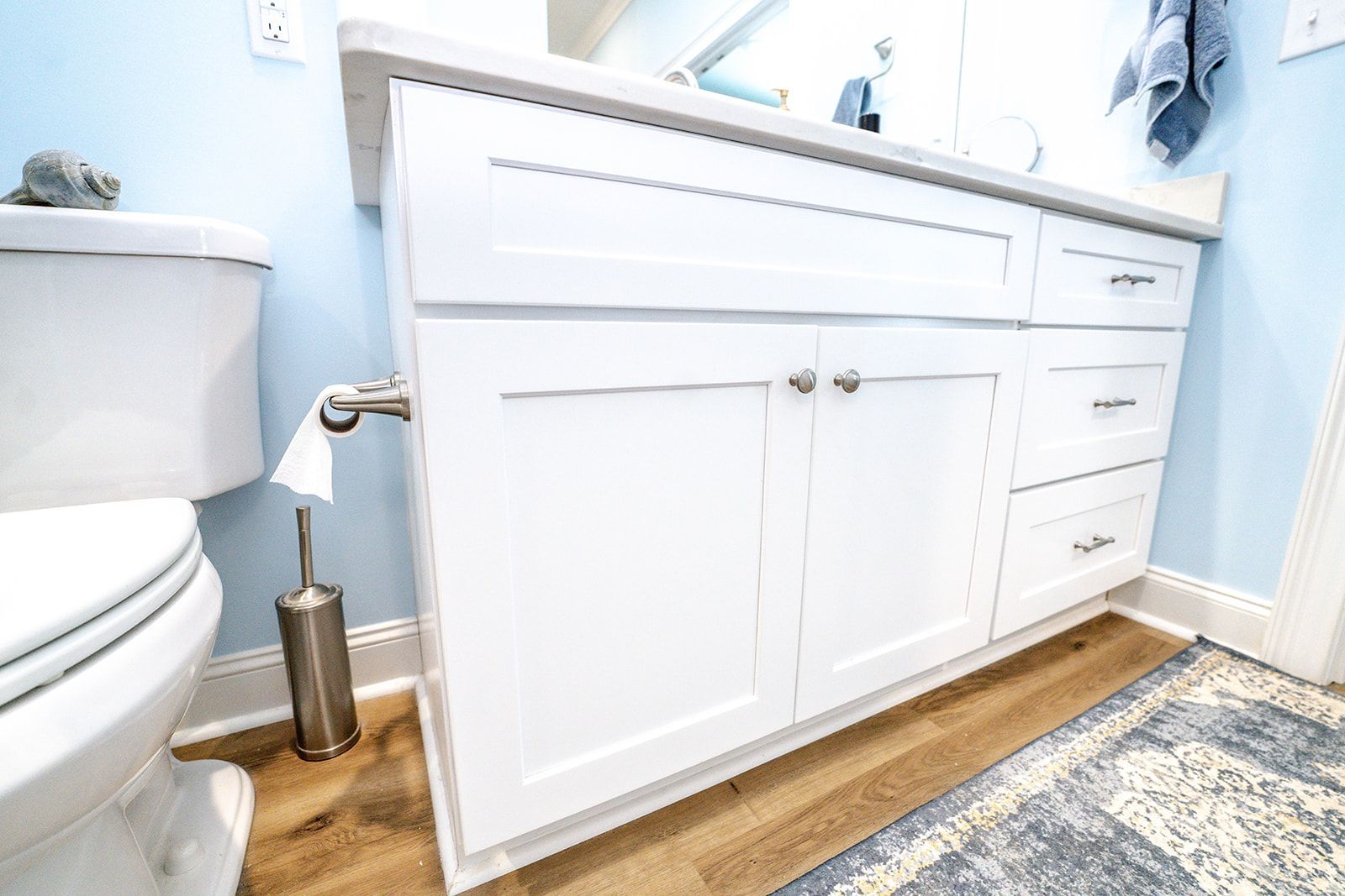 A bathroom with white cabinets , a toilet , and a sink.