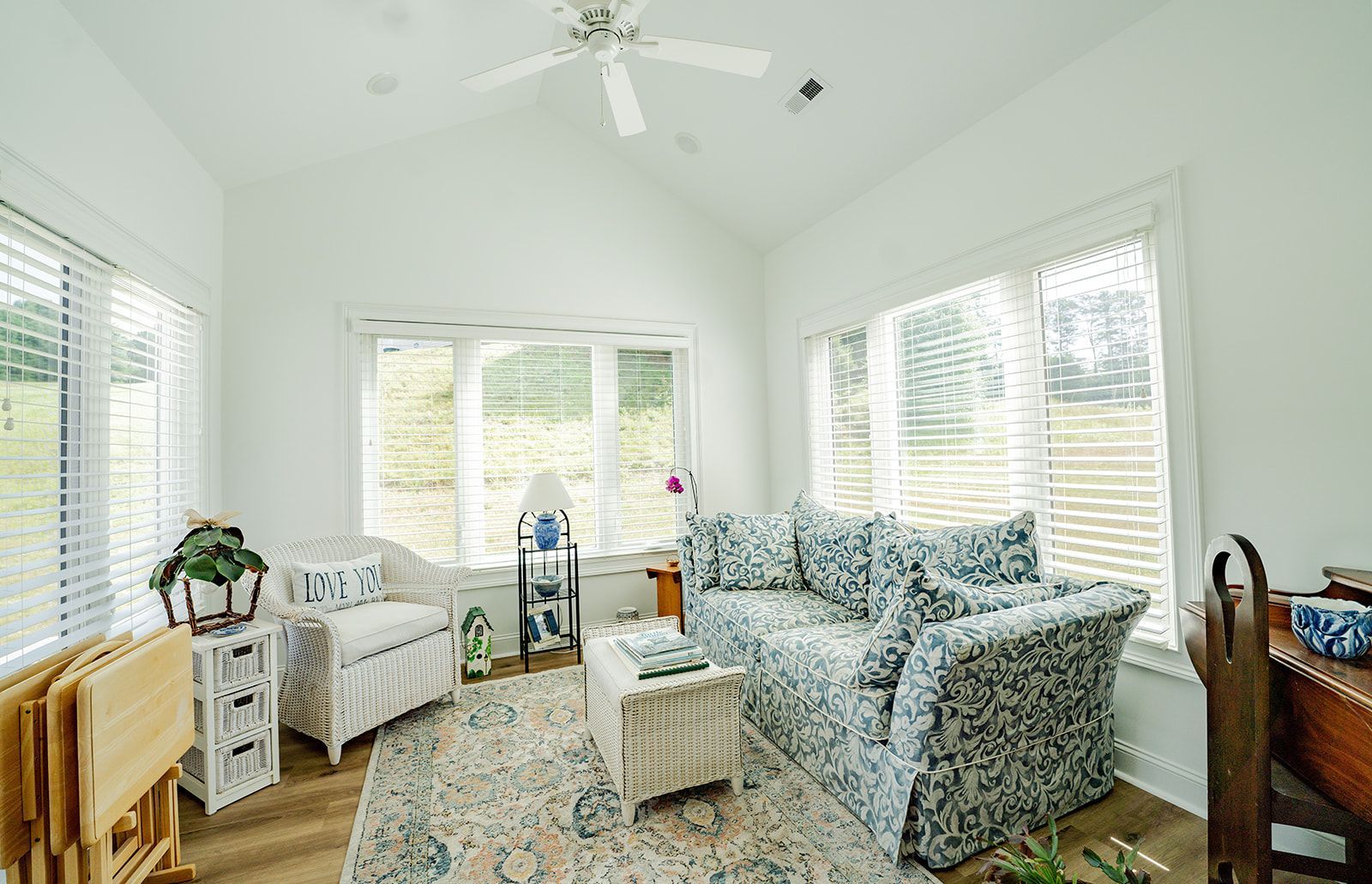 A living room with a couch , chair , table and ceiling fan.