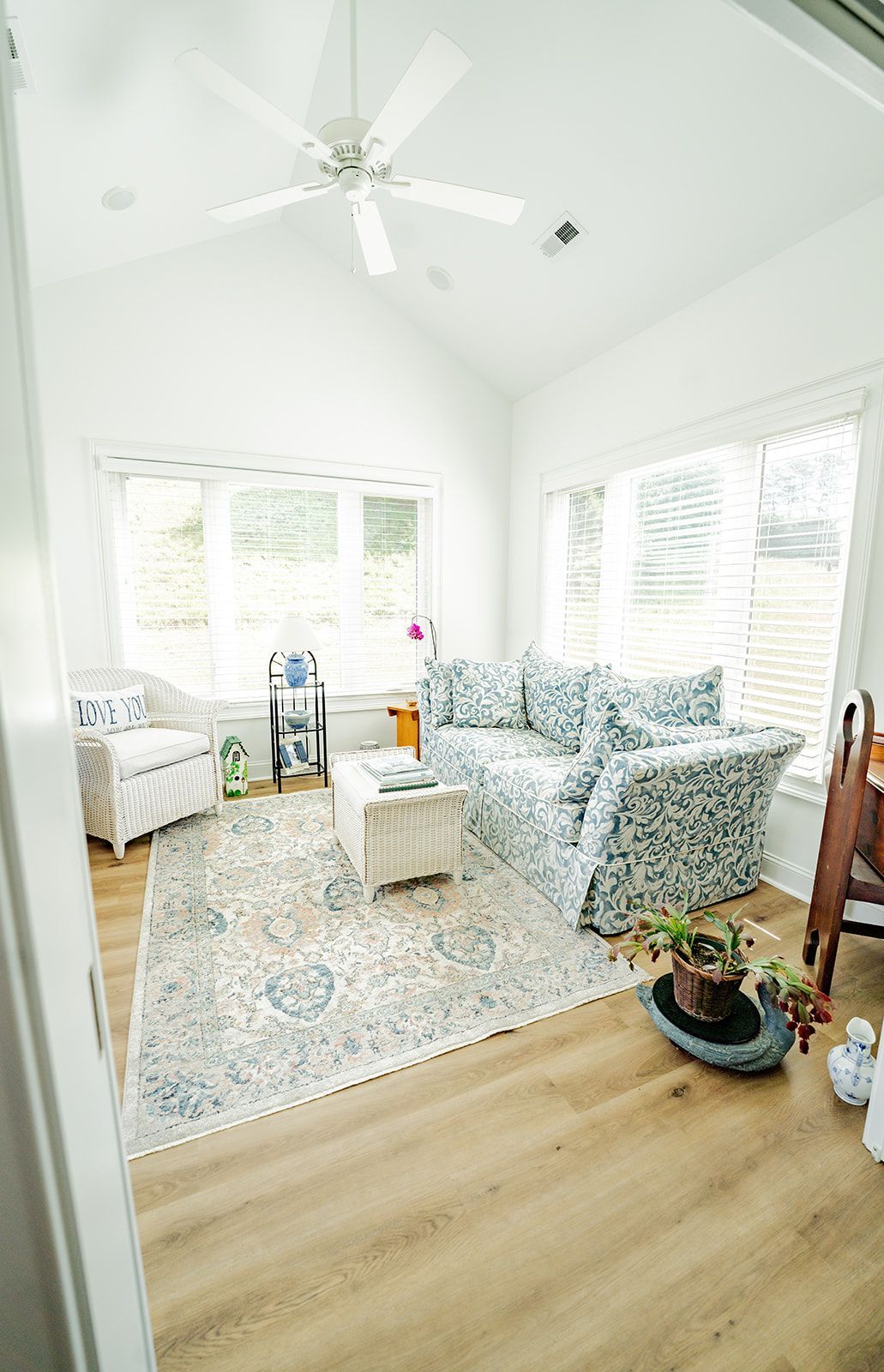 A living room with a couch , chair , coffee table and ceiling fan.
