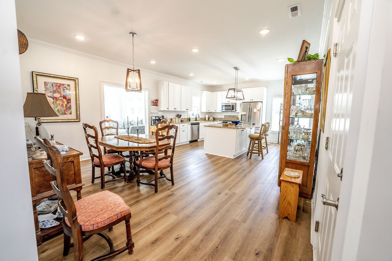 A living room with a table and chairs and a kitchen in the background.