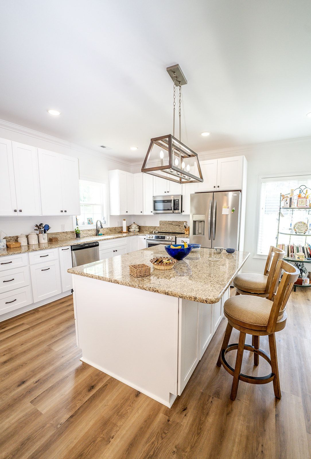 A kitchen with white cabinets , granite counter tops , stainless steel appliances and a large island.