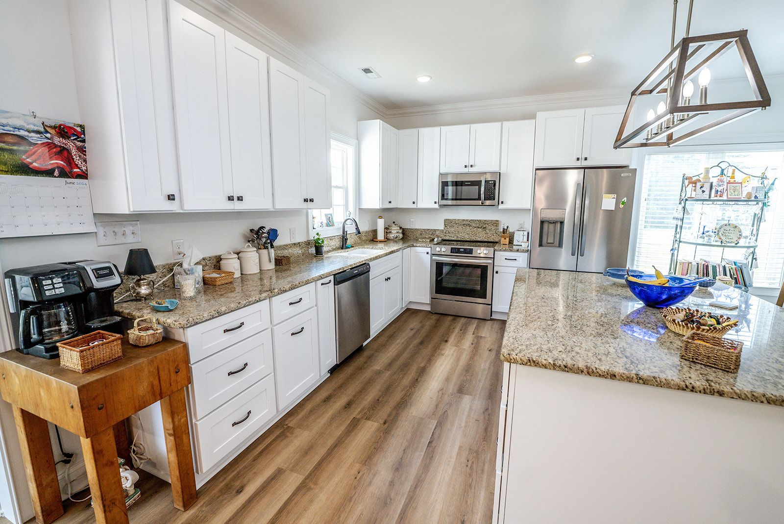 A kitchen with white cabinets , granite counter tops , stainless steel appliances and a large island.