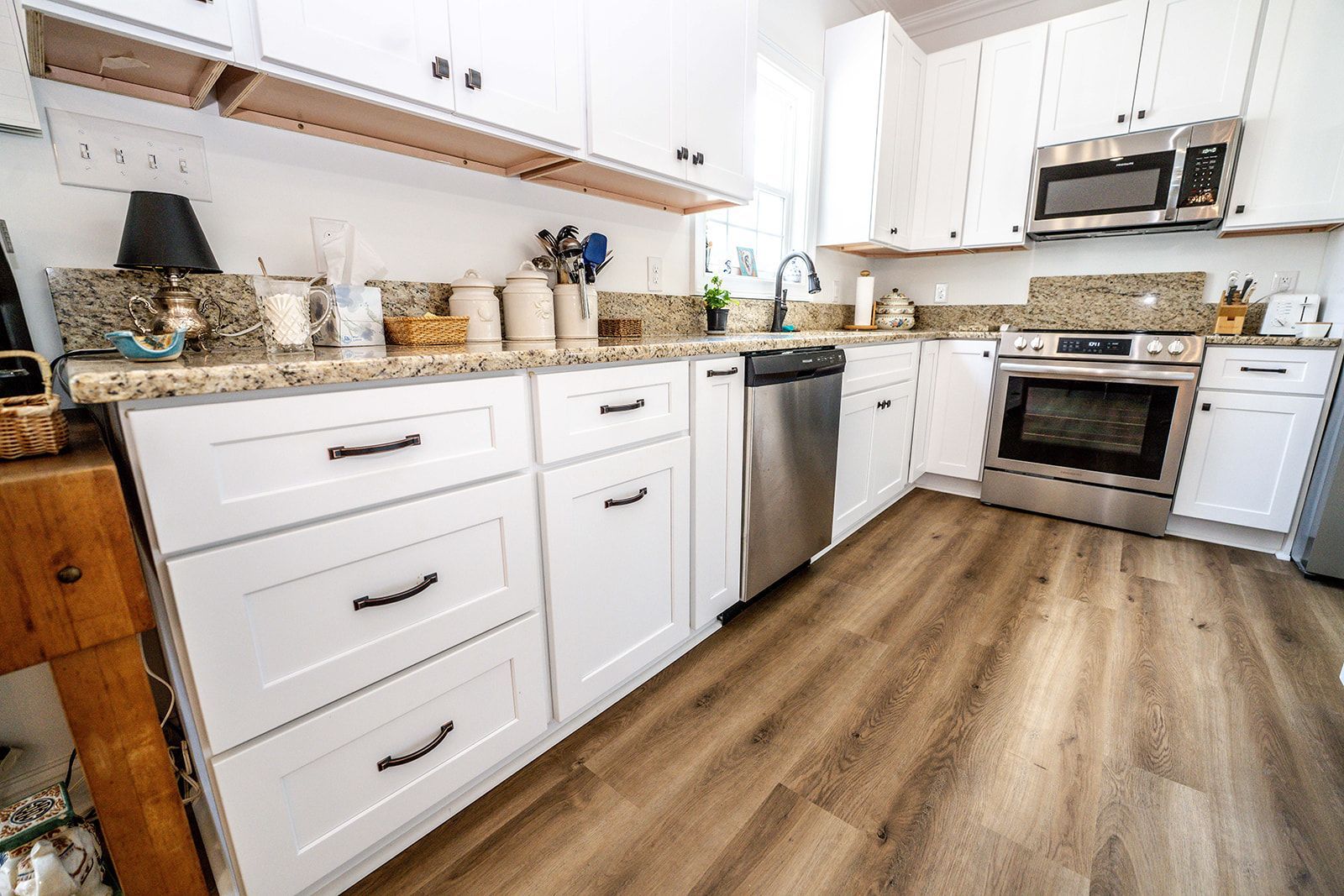 A kitchen with white cabinets , stainless steel appliances , and hardwood floors.