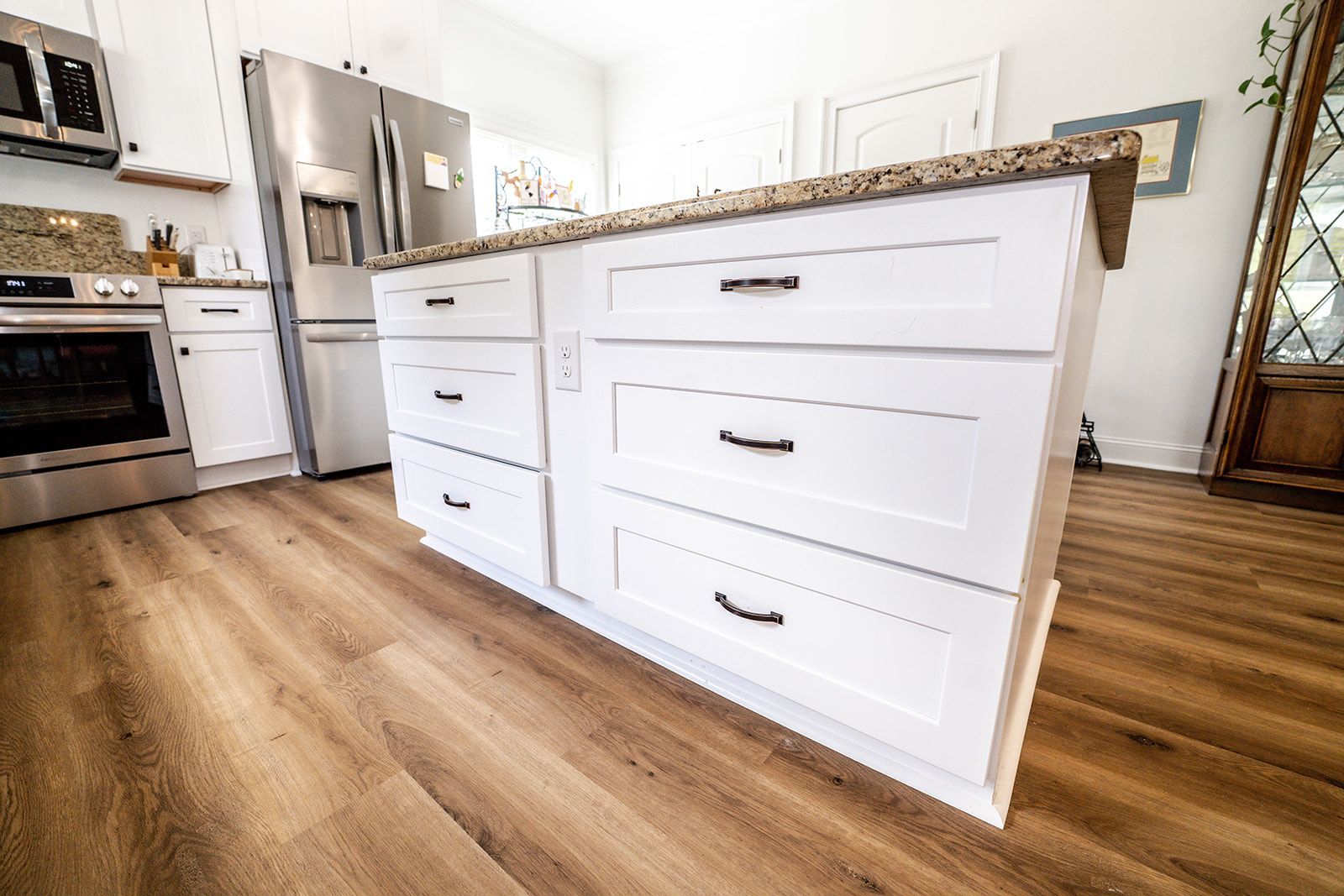 A kitchen with white cabinets , stainless steel appliances , and a large island.