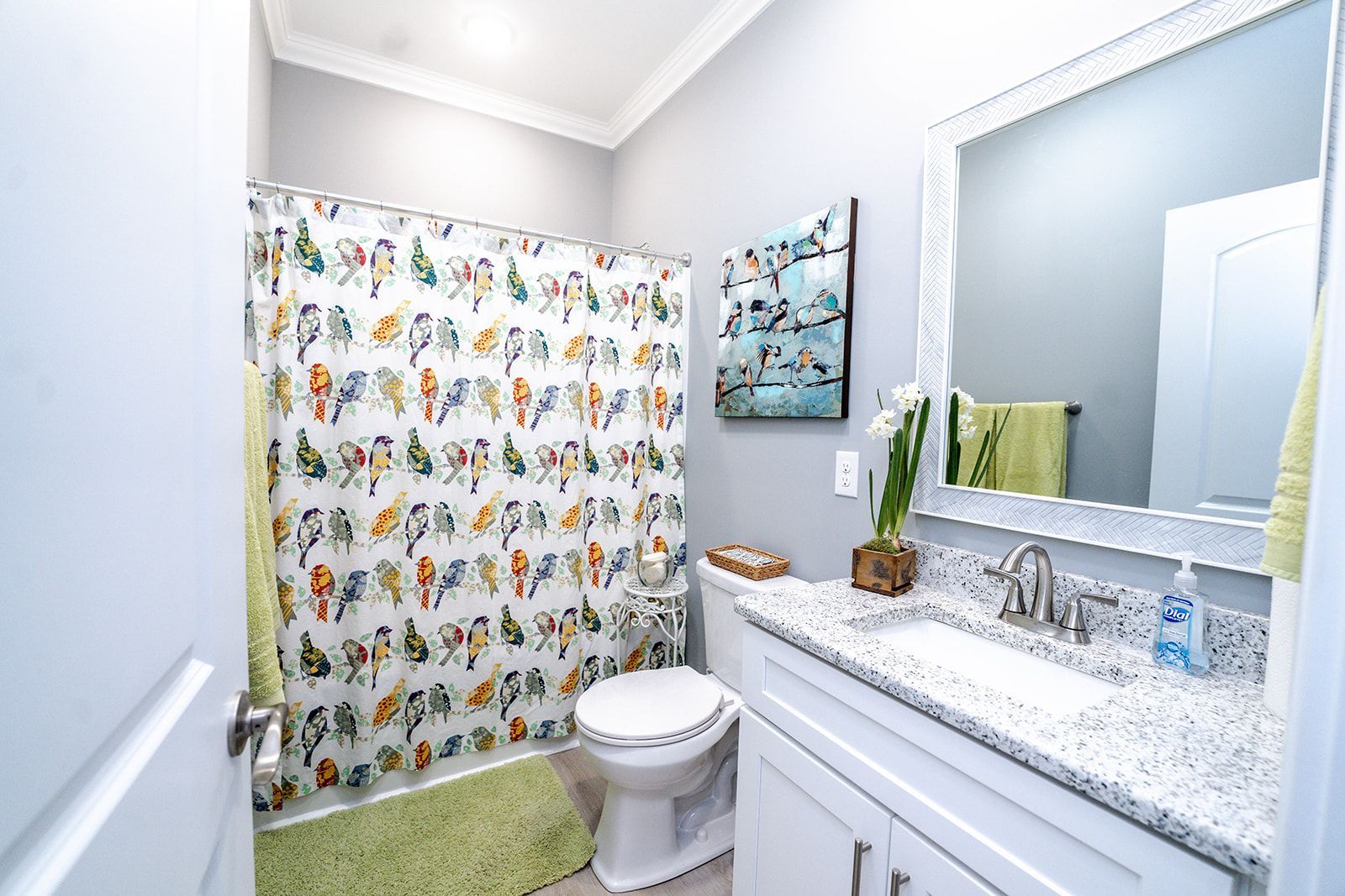 A bathroom with a toilet , sink , mirror and shower curtain.