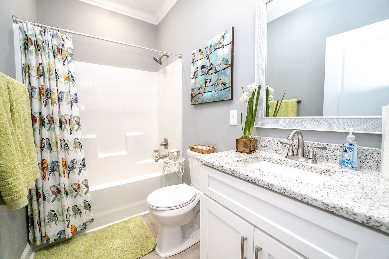 A bathroom with a toilet , sink , shower and mirror.
