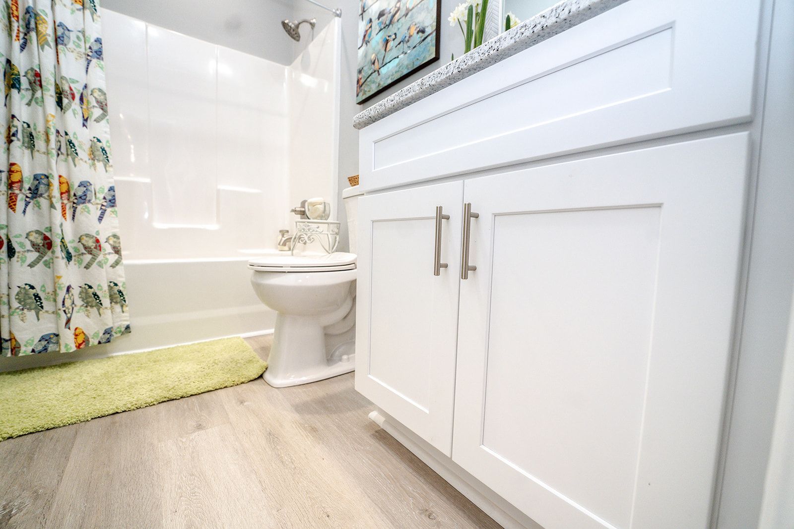 A bathroom with white cabinets , a toilet , a bathtub and a shower curtain.
