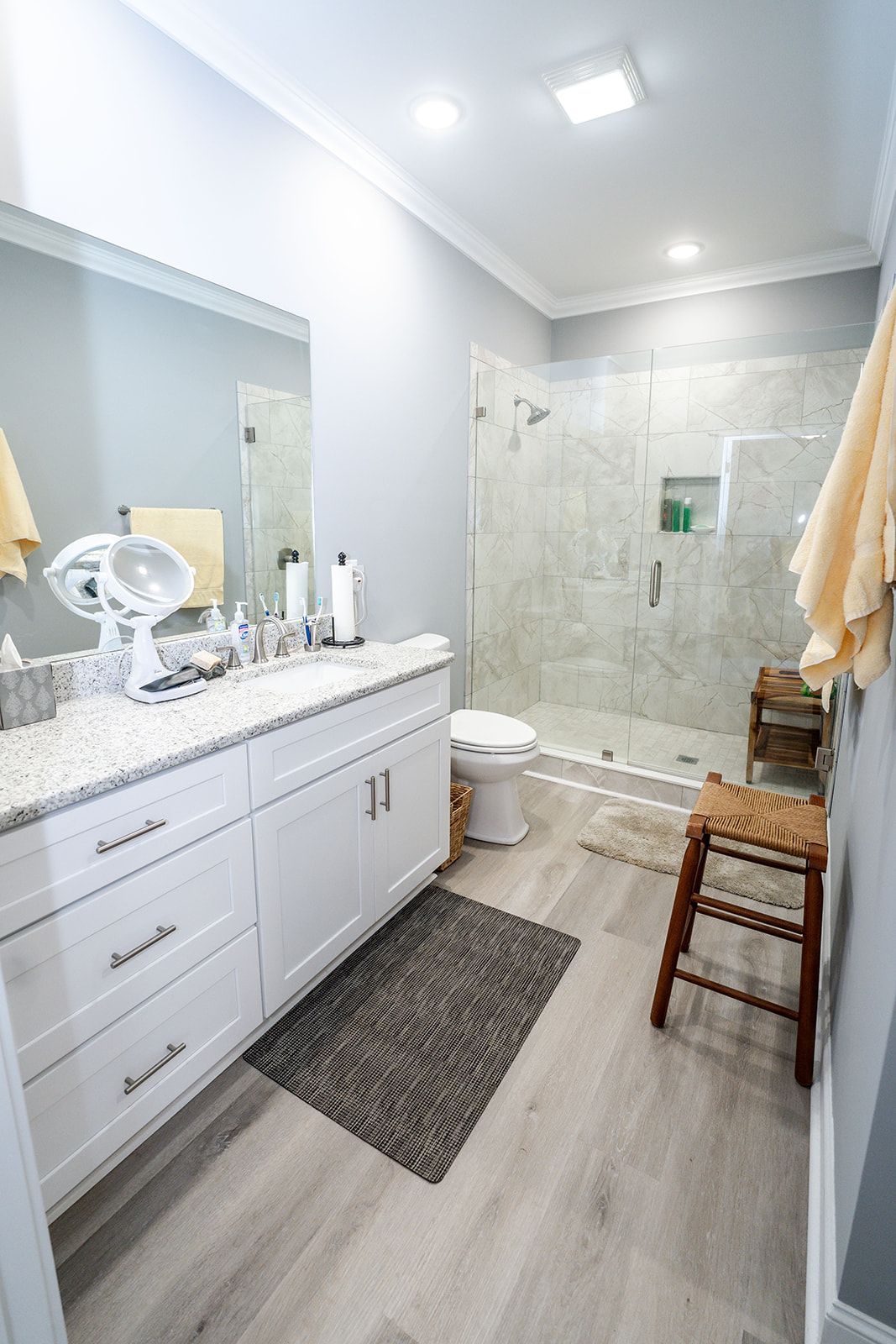 A bathroom with a toilet , sink , mirror and walk in shower.