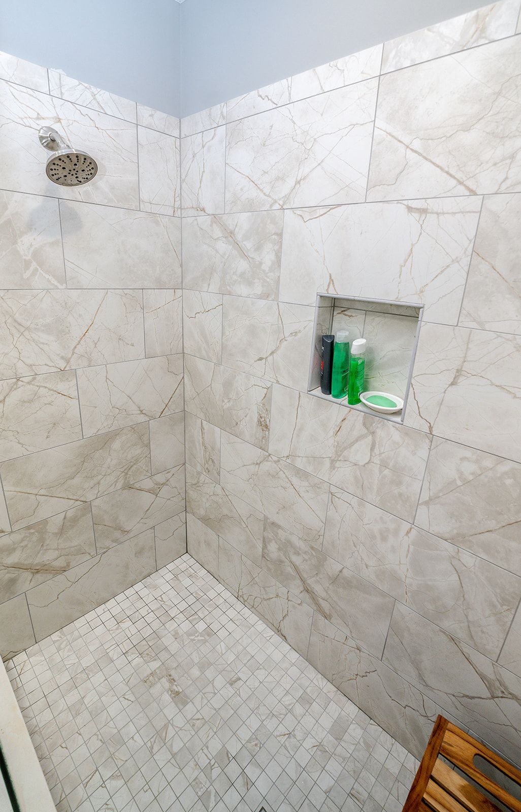 A bathroom with a walk in shower and a wooden chair.