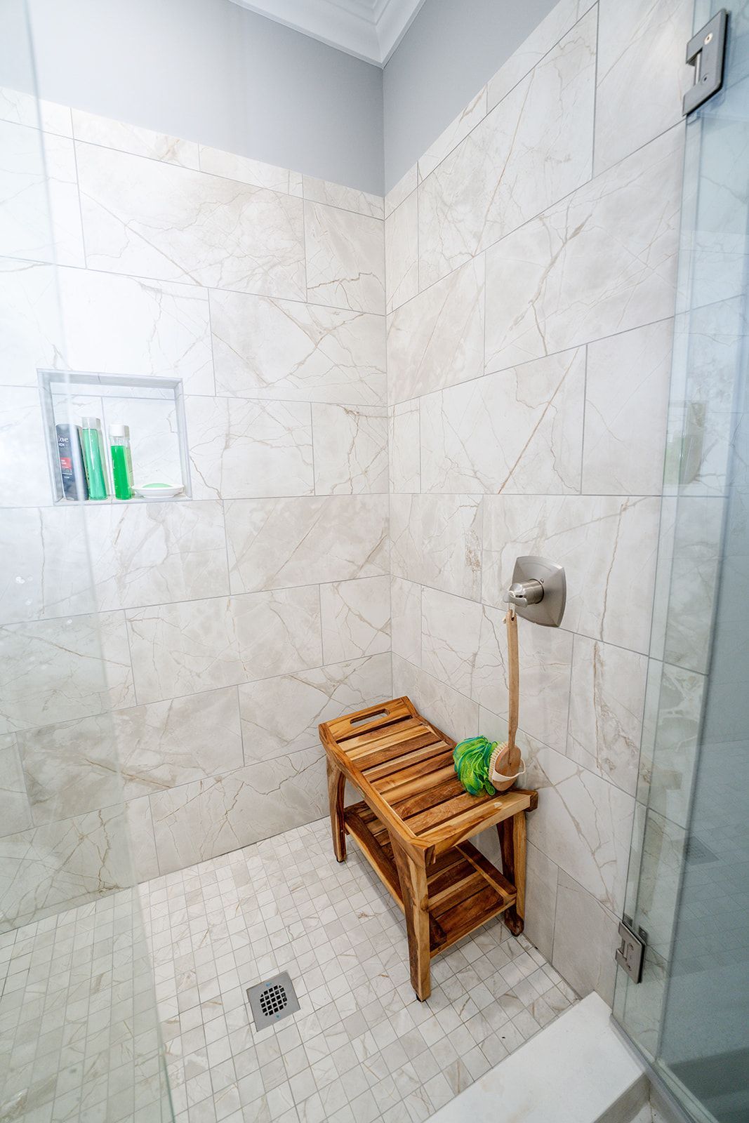A bathroom with a walk in shower and a wooden bench.