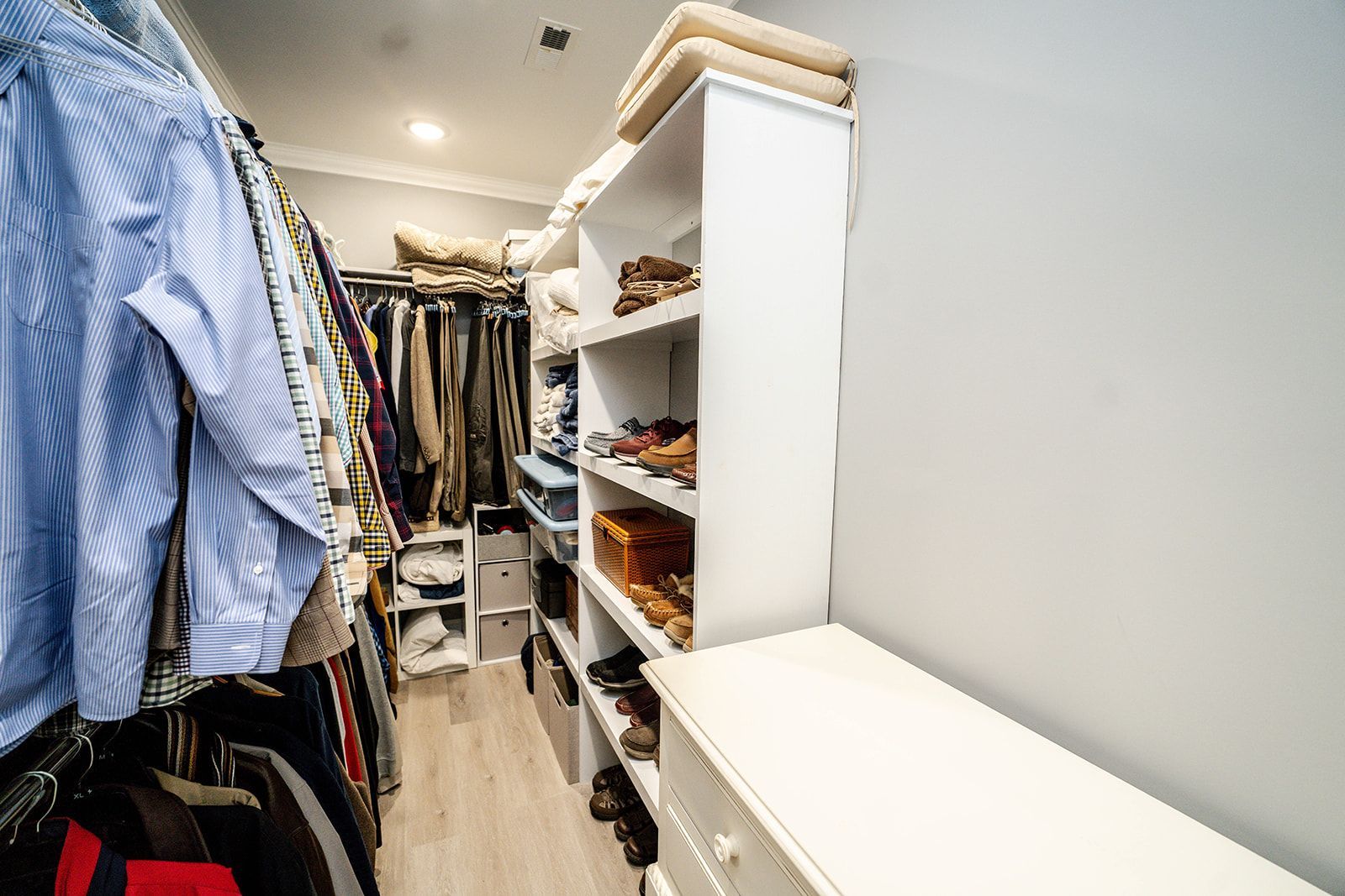 A walk in closet filled with lots of clothes and shoes.