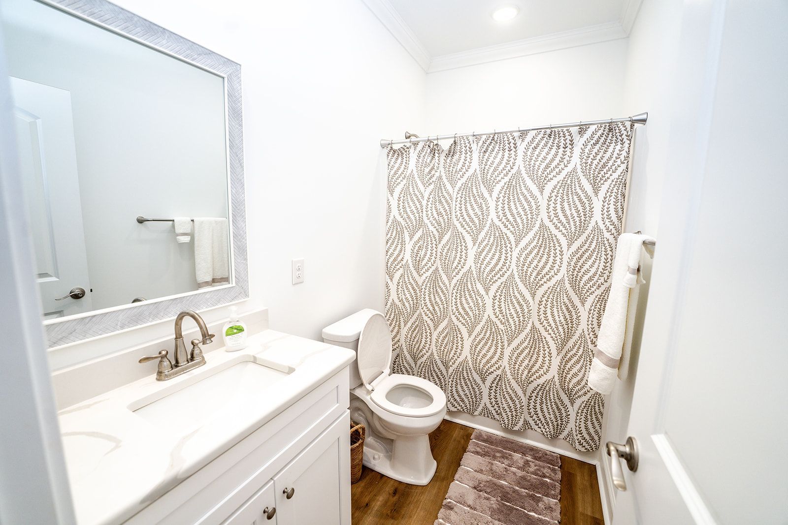 A bathroom with a toilet , sink , mirror and shower curtain.