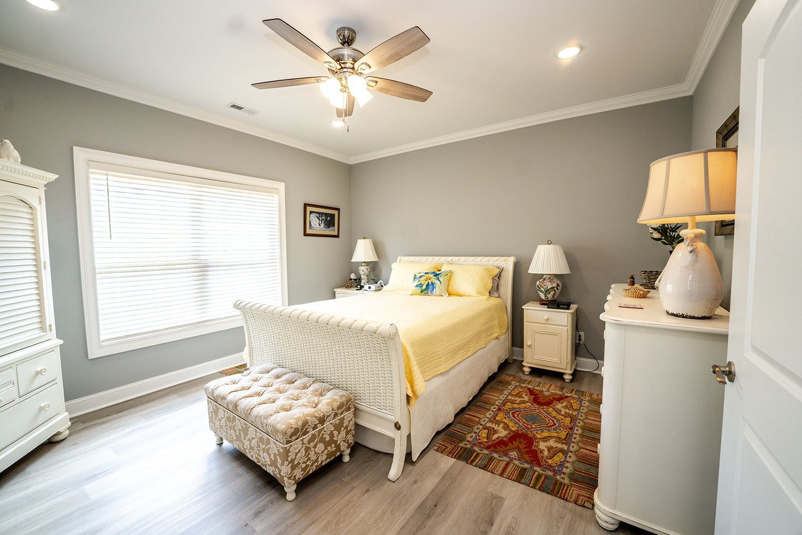 A bedroom with a bed , dresser , nightstand , and ceiling fan.