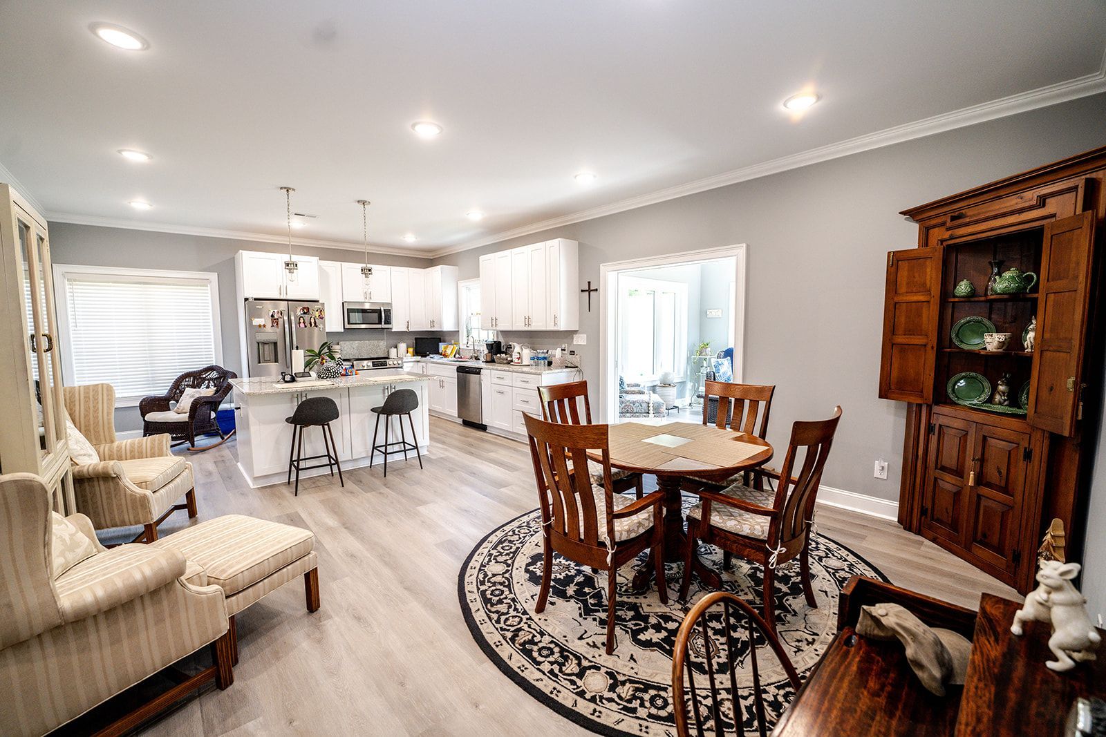 A living room with a table and chairs and a kitchen in the background.