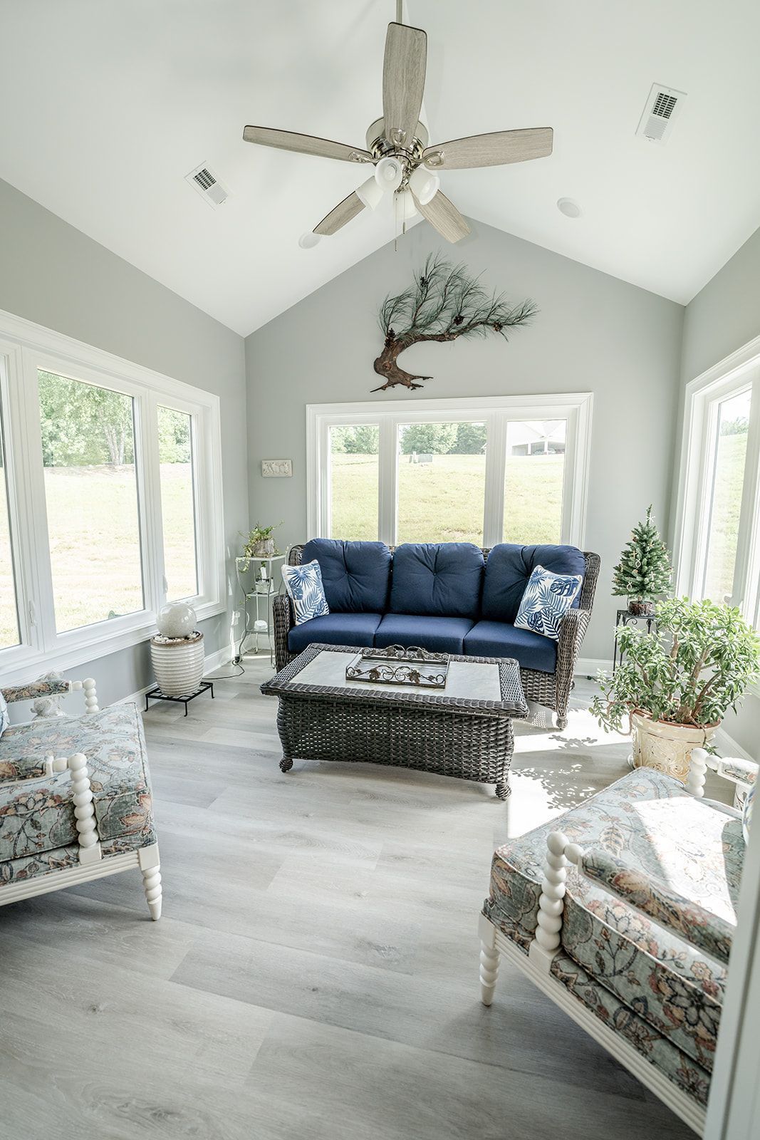 A living room with a blue couch and a ceiling fan.
