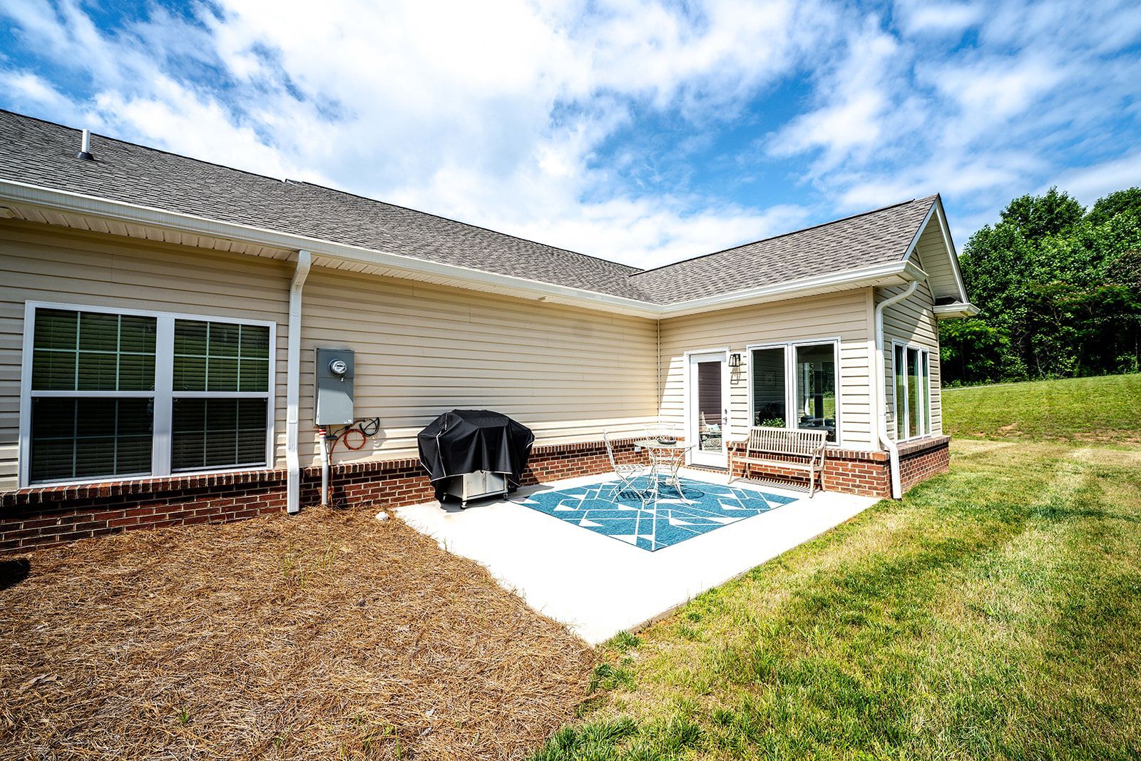 The backyard of a house with a hot tub and a grill.