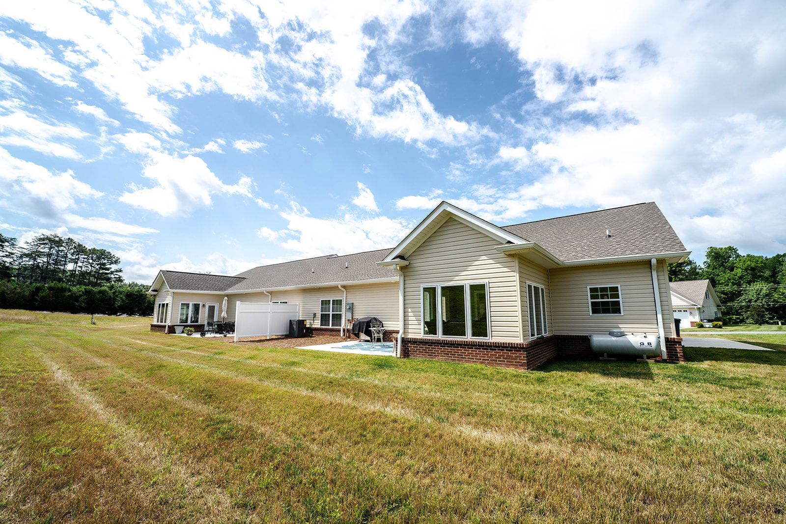 A large house is sitting on top of a lush green field.