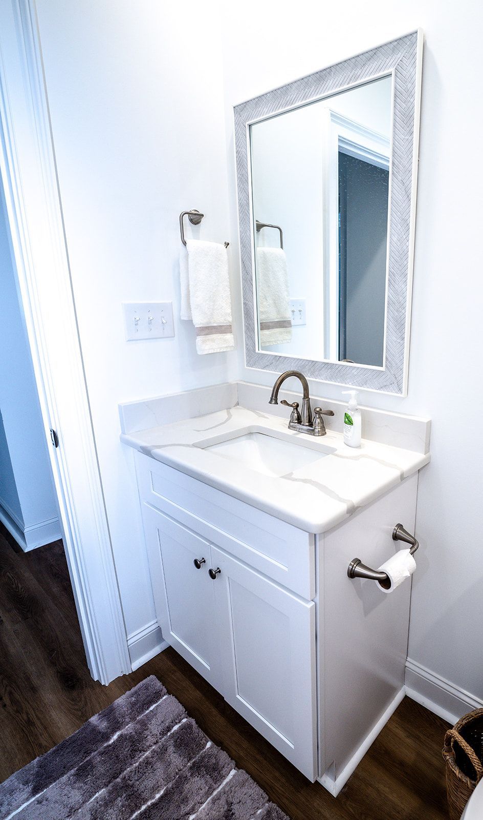A bathroom with a sink , mirror and towel rack.