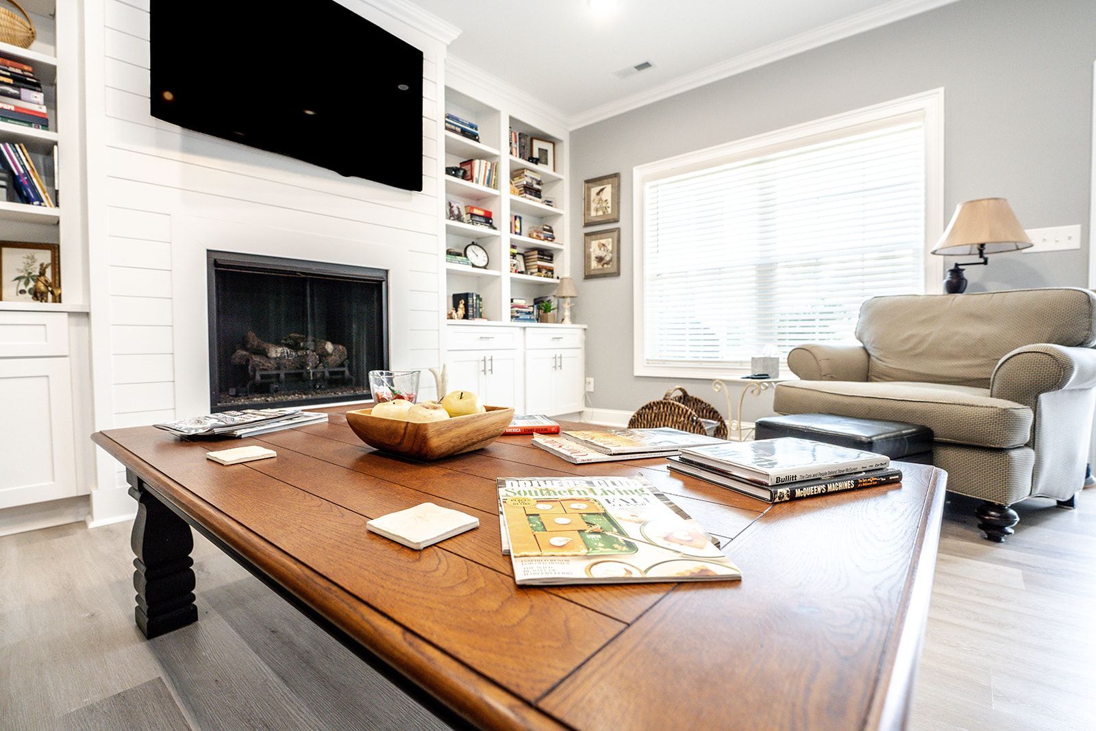 A living room with a coffee table , chair , fireplace and television.