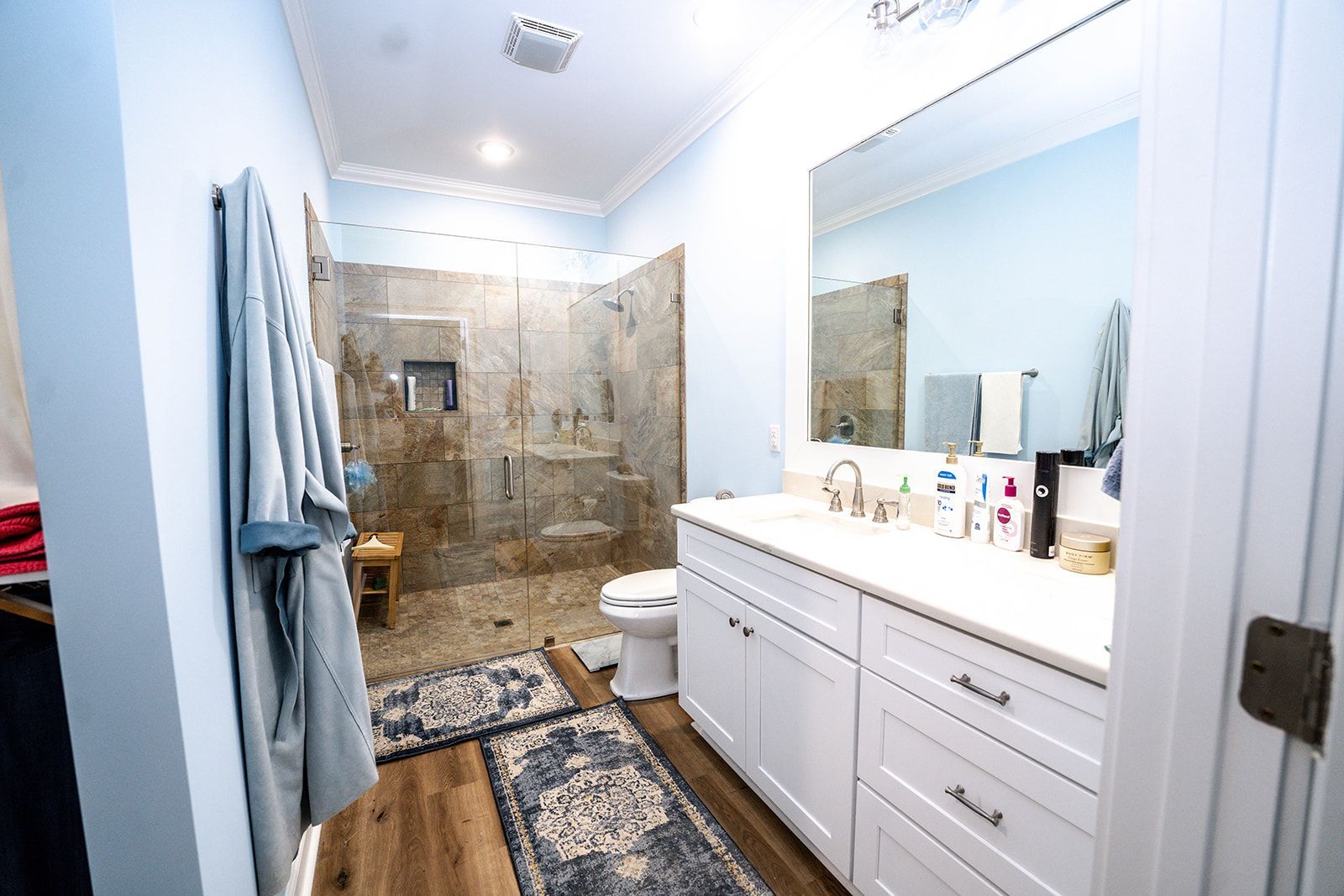 A bathroom with a walk in shower , sink , toilet and mirror.