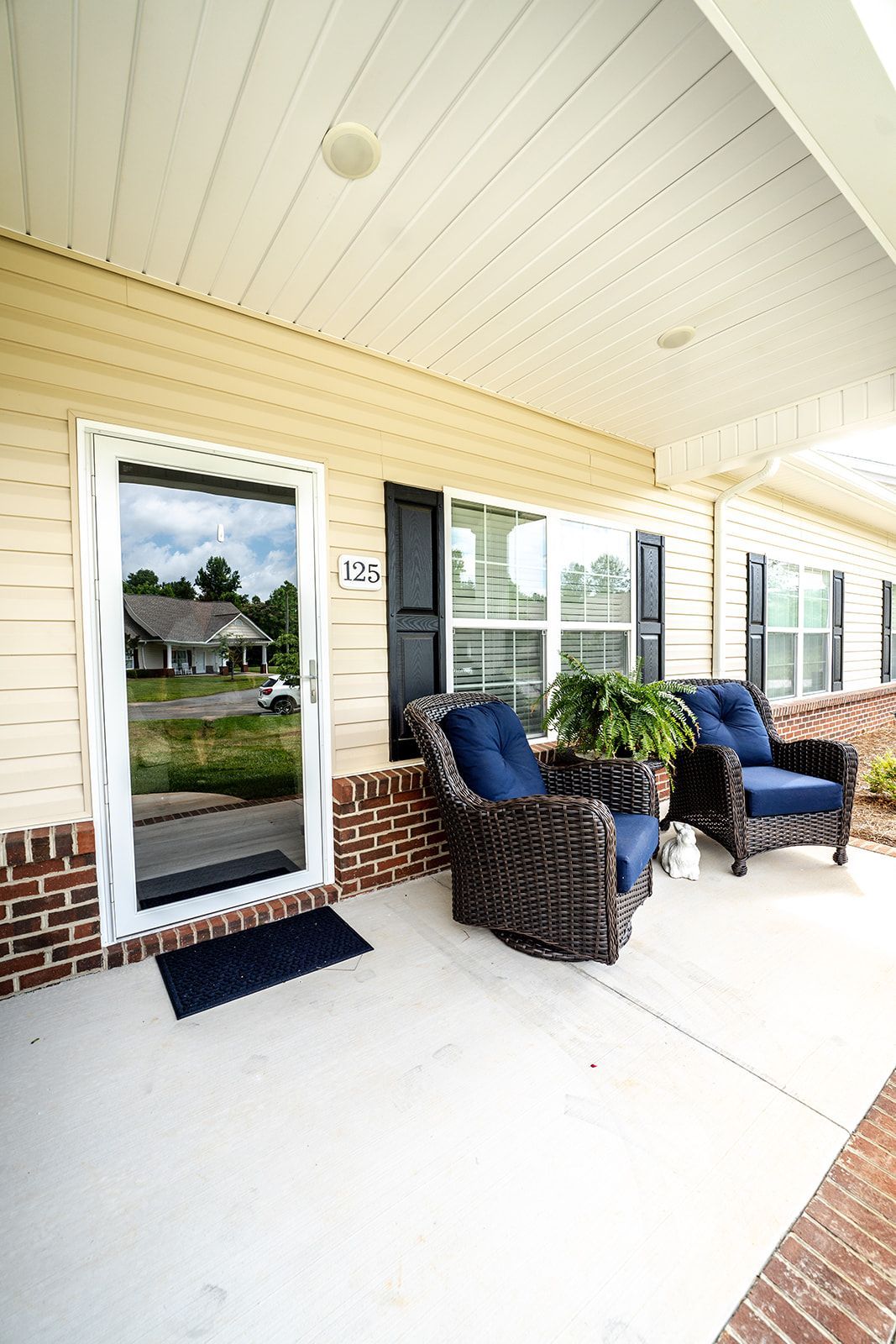 There are two chairs on the porch of a house.