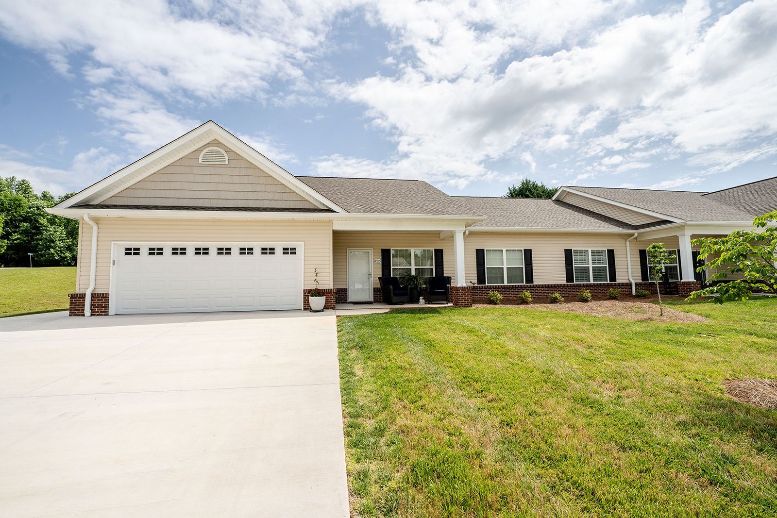 A large house with a white garage door is sitting on top of a lush green hillside.