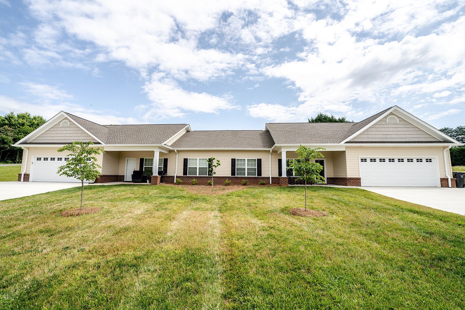 A large house with two garages and a large lawn in front of it.