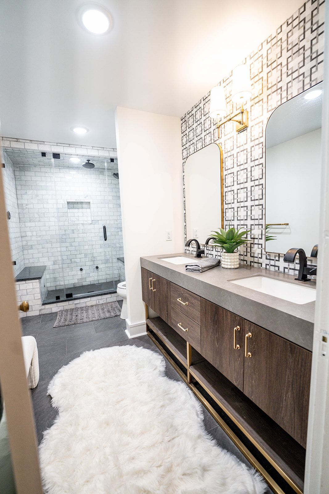 A bathroom with two sinks , a toilet and a shower.