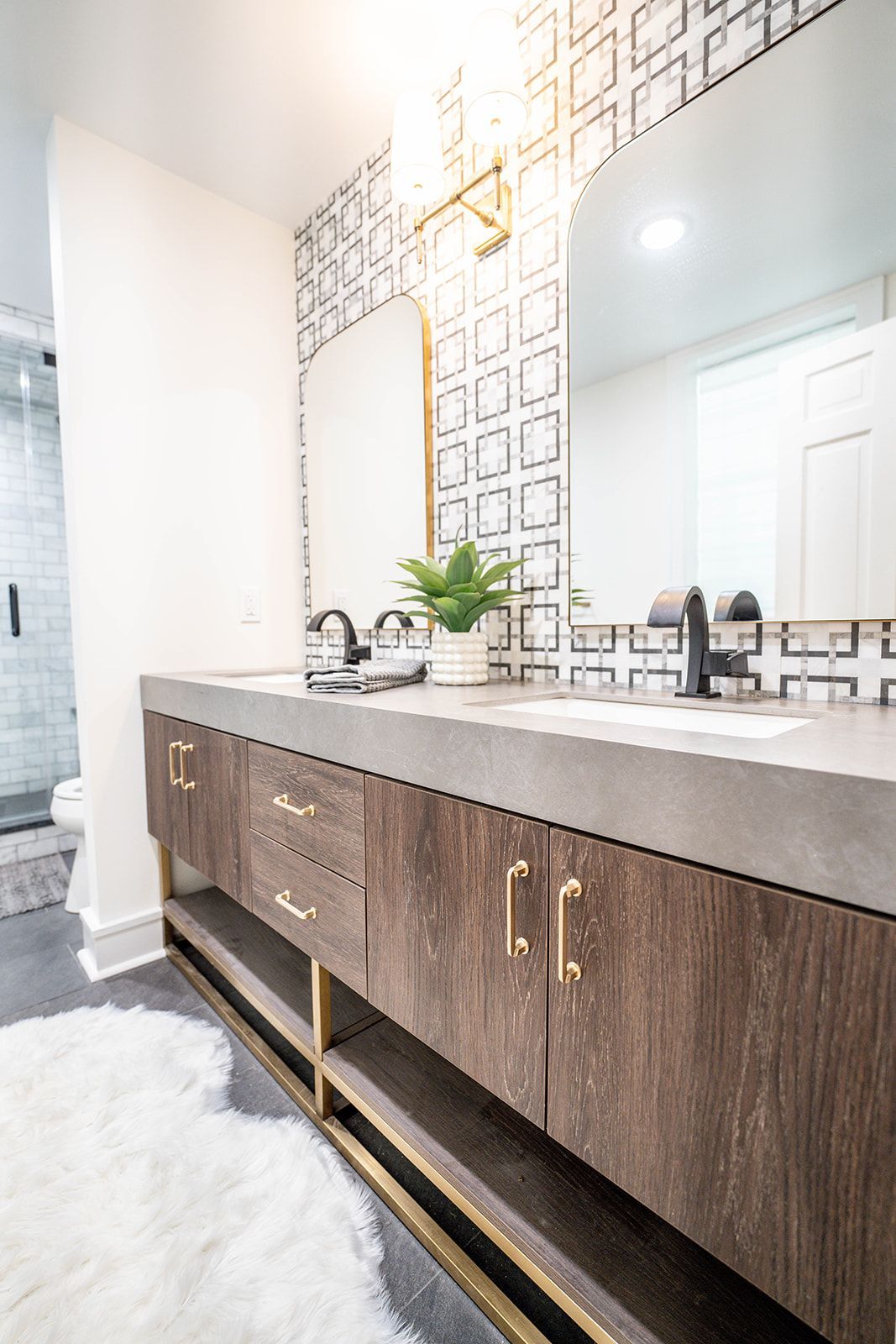 A bathroom with two sinks , a mirror and a rug.