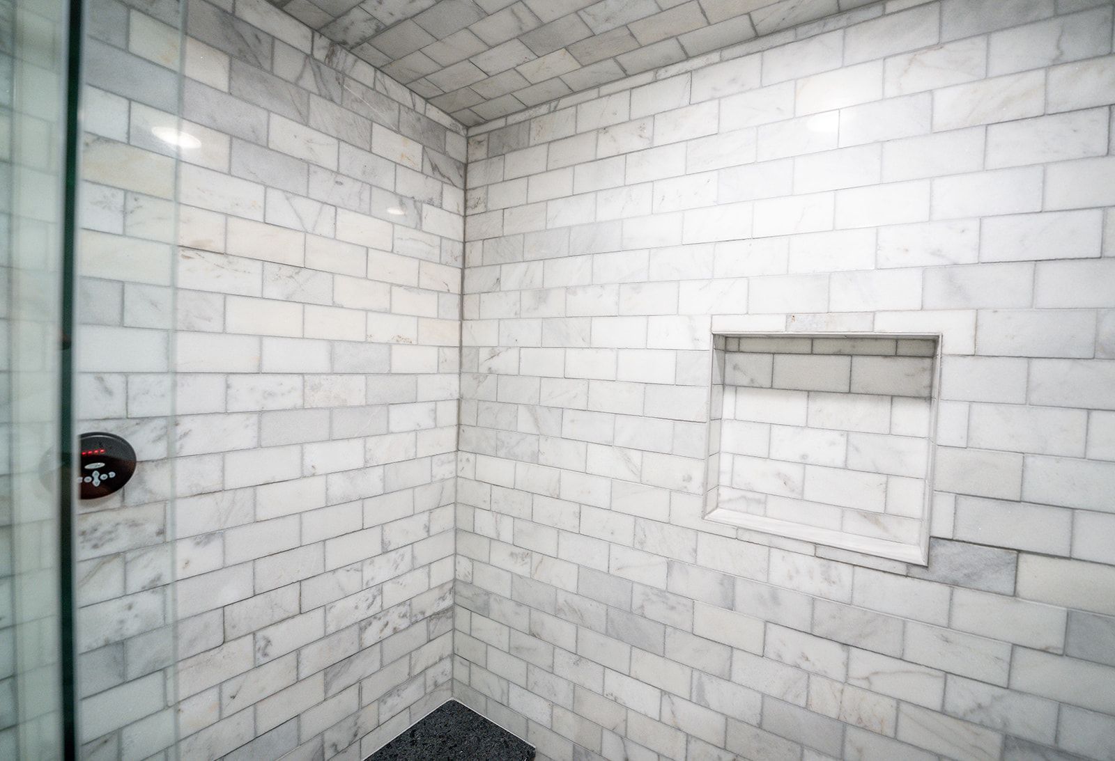 A bathroom with white brick walls and a walk in shower.