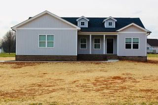 A white house with a blue roof is sitting in the middle of a field.