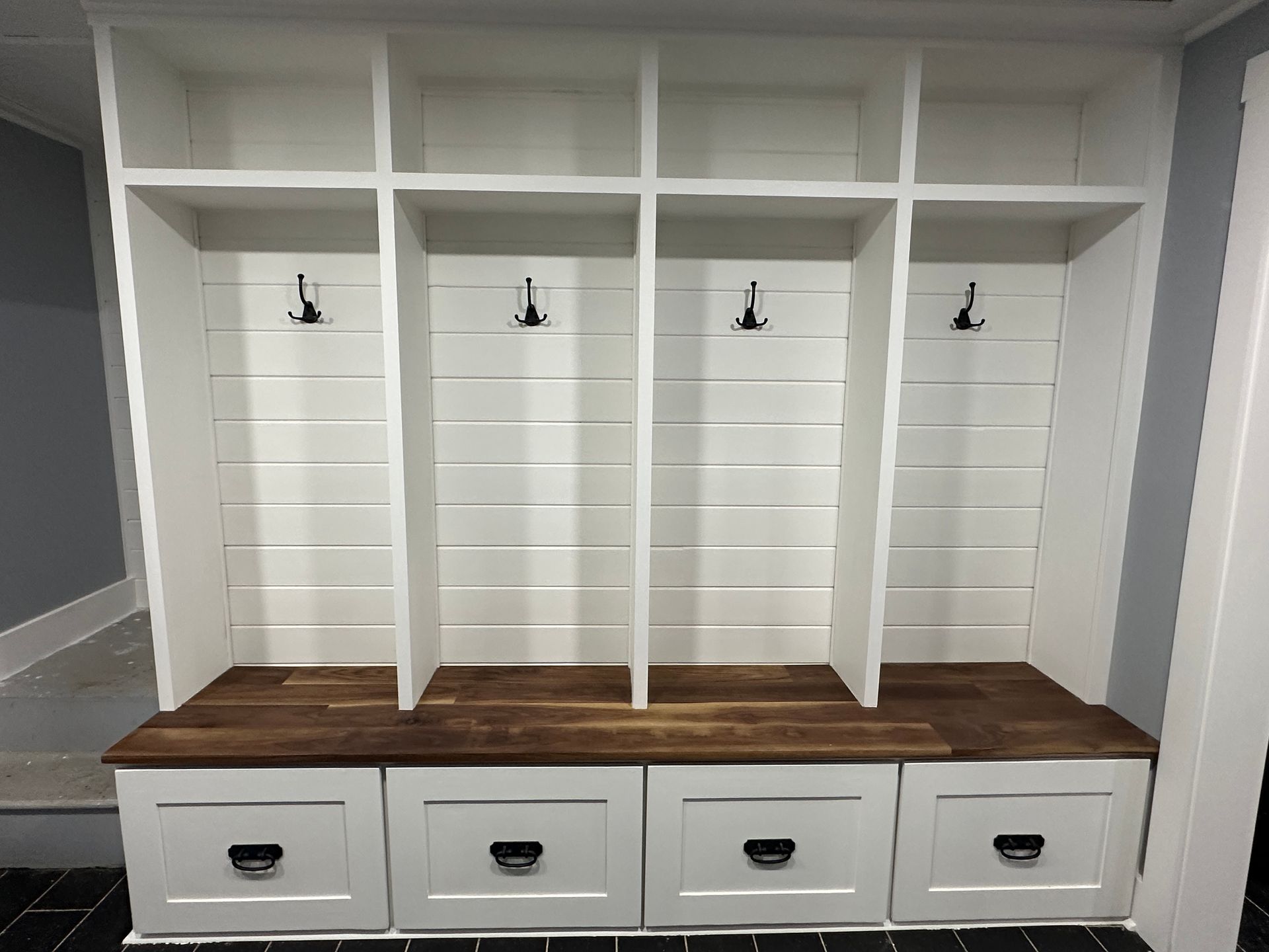 A white shelf with drawers and hooks in a hallway.