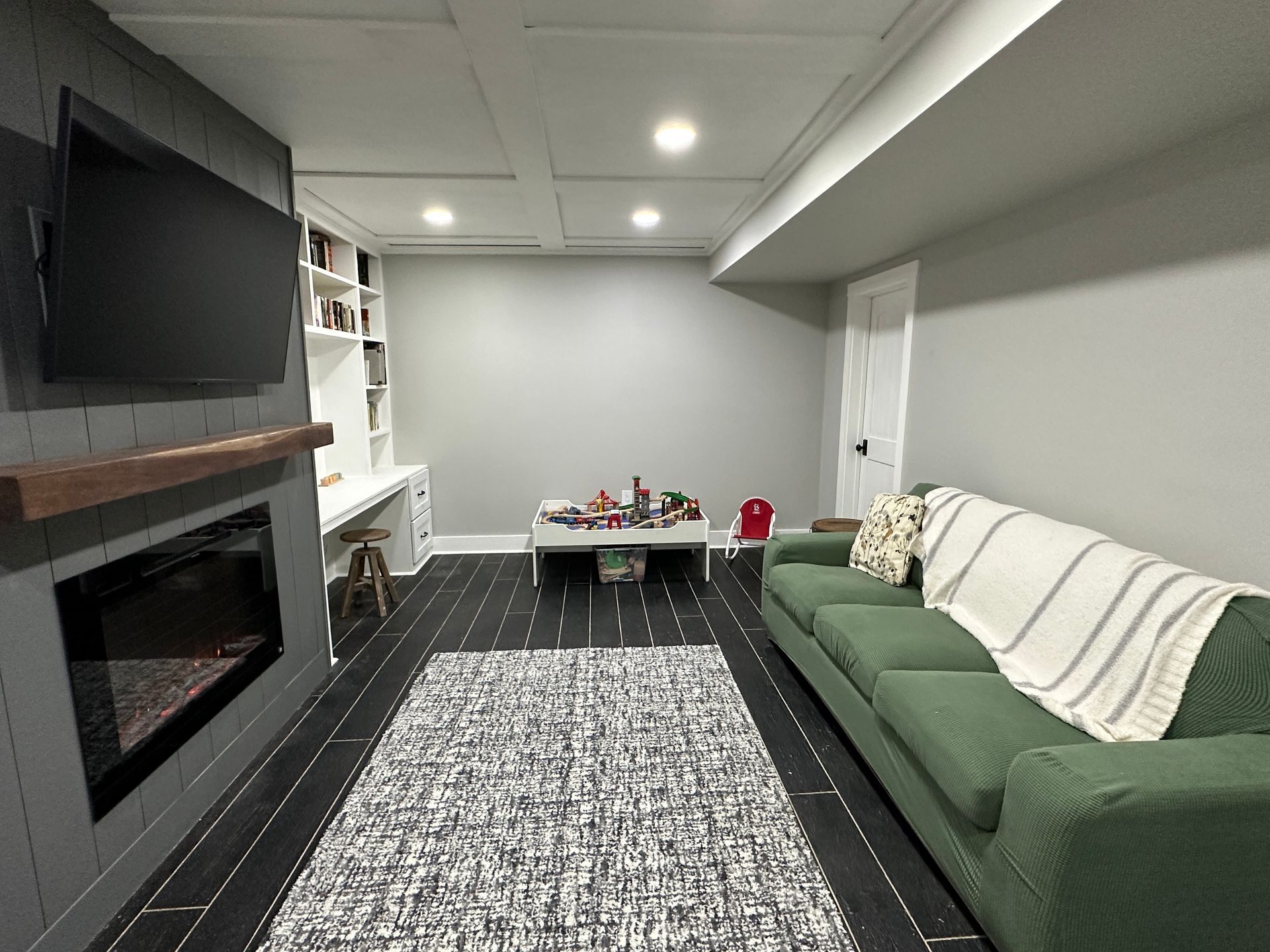 A living room with a green couch and a fireplace
