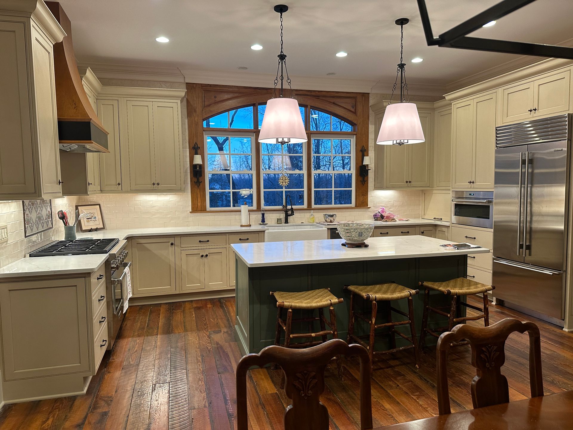 A kitchen with white cabinets and stainless steel appliances and a large island in the middle.