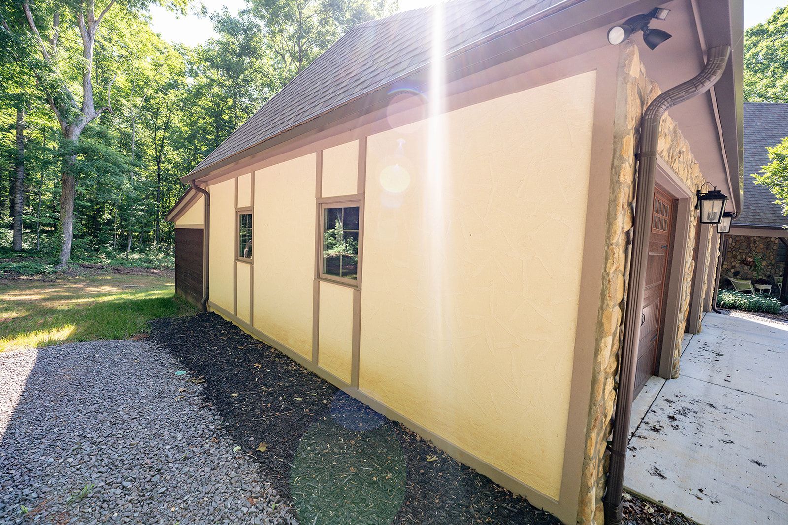 The side of a house with a lot of windows and trees in the background.