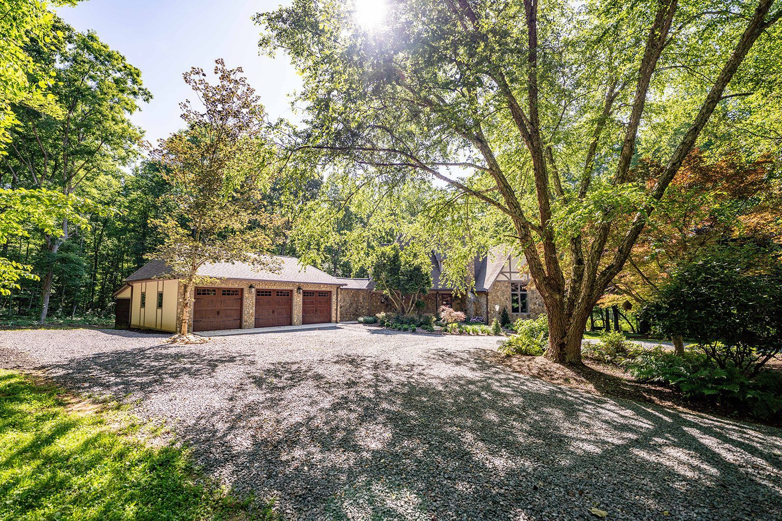 A house with a garage and a driveway surrounded by trees.
