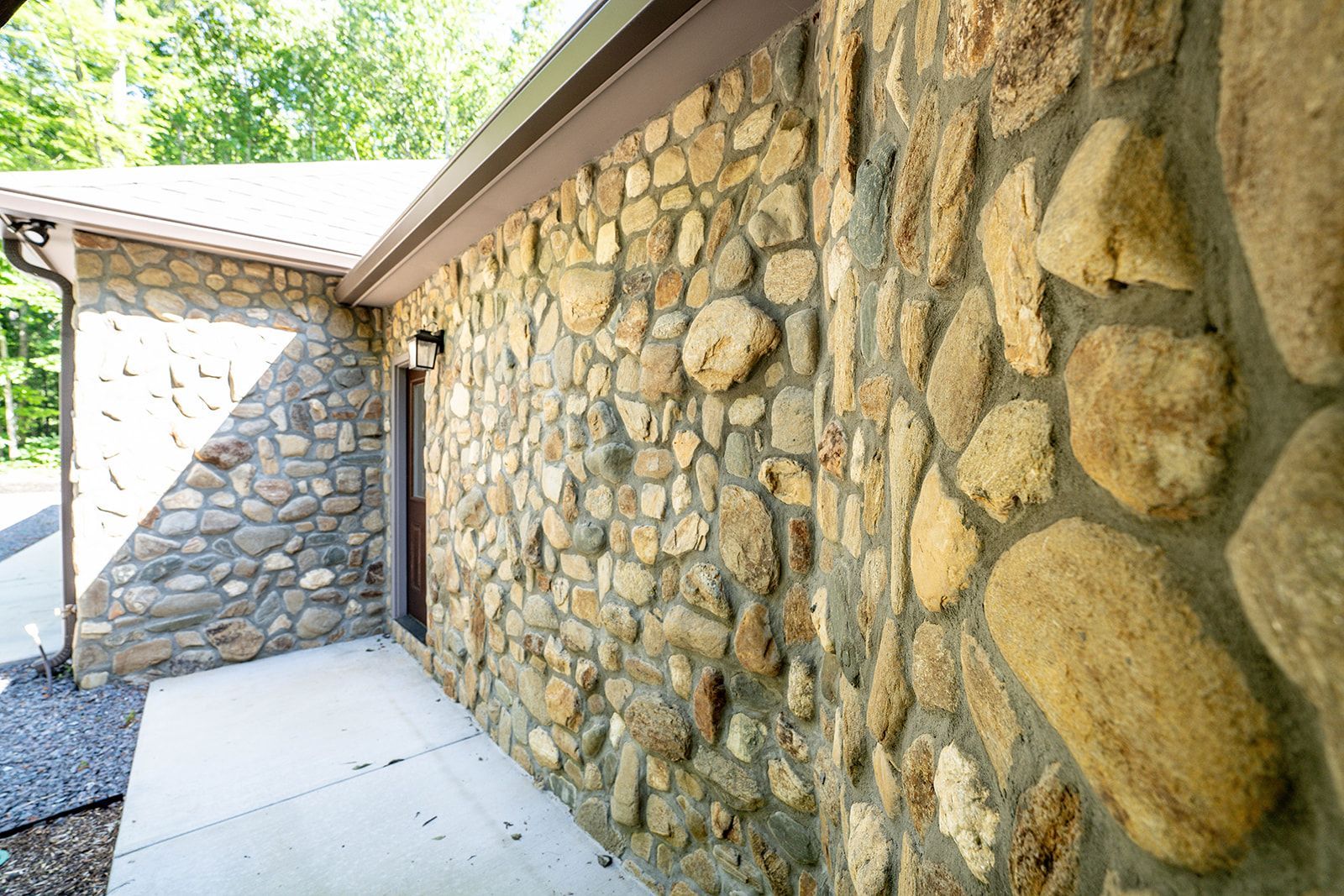 A stone wall with a concrete walkway leading to it