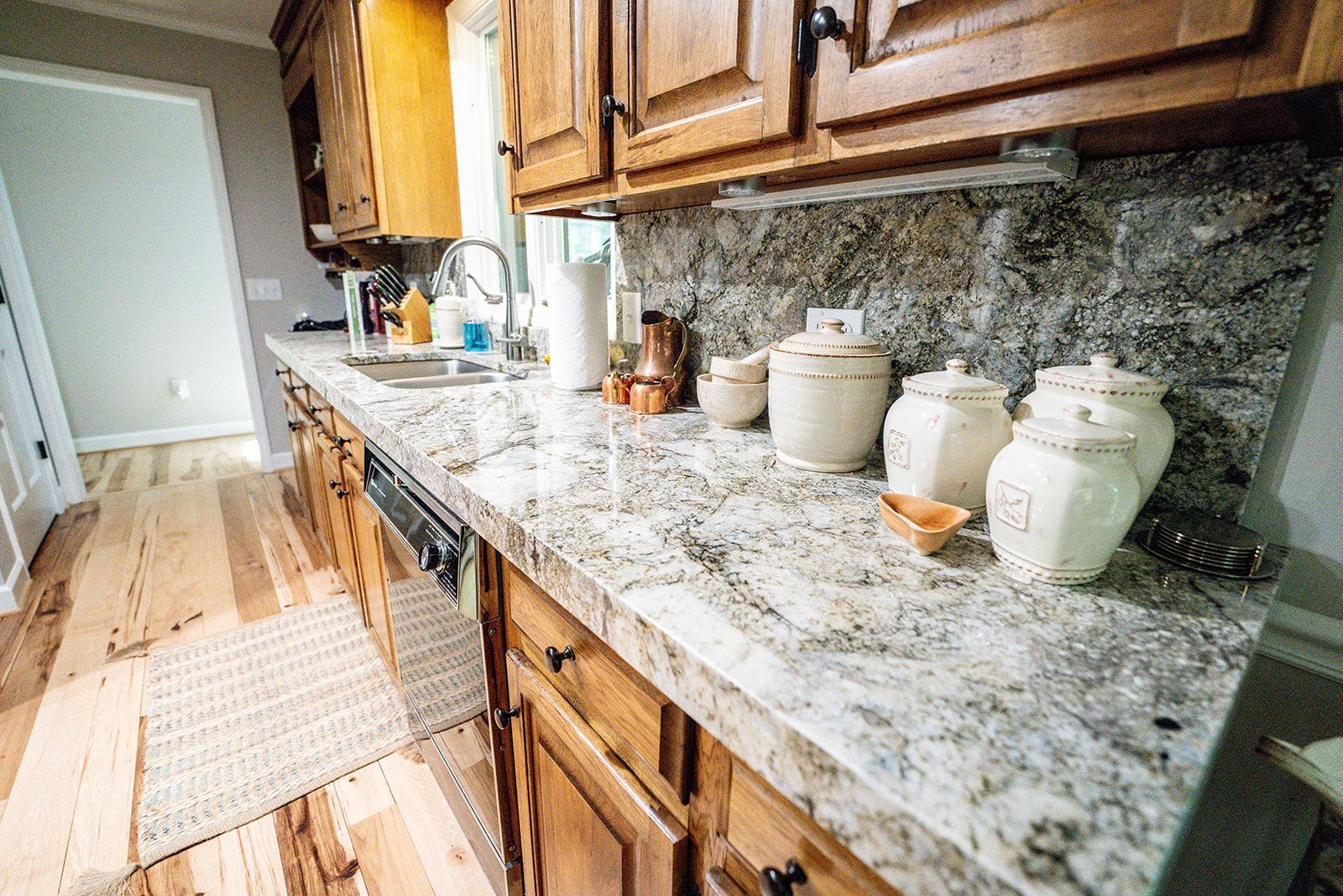 A kitchen with granite counter tops and wooden cabinets.